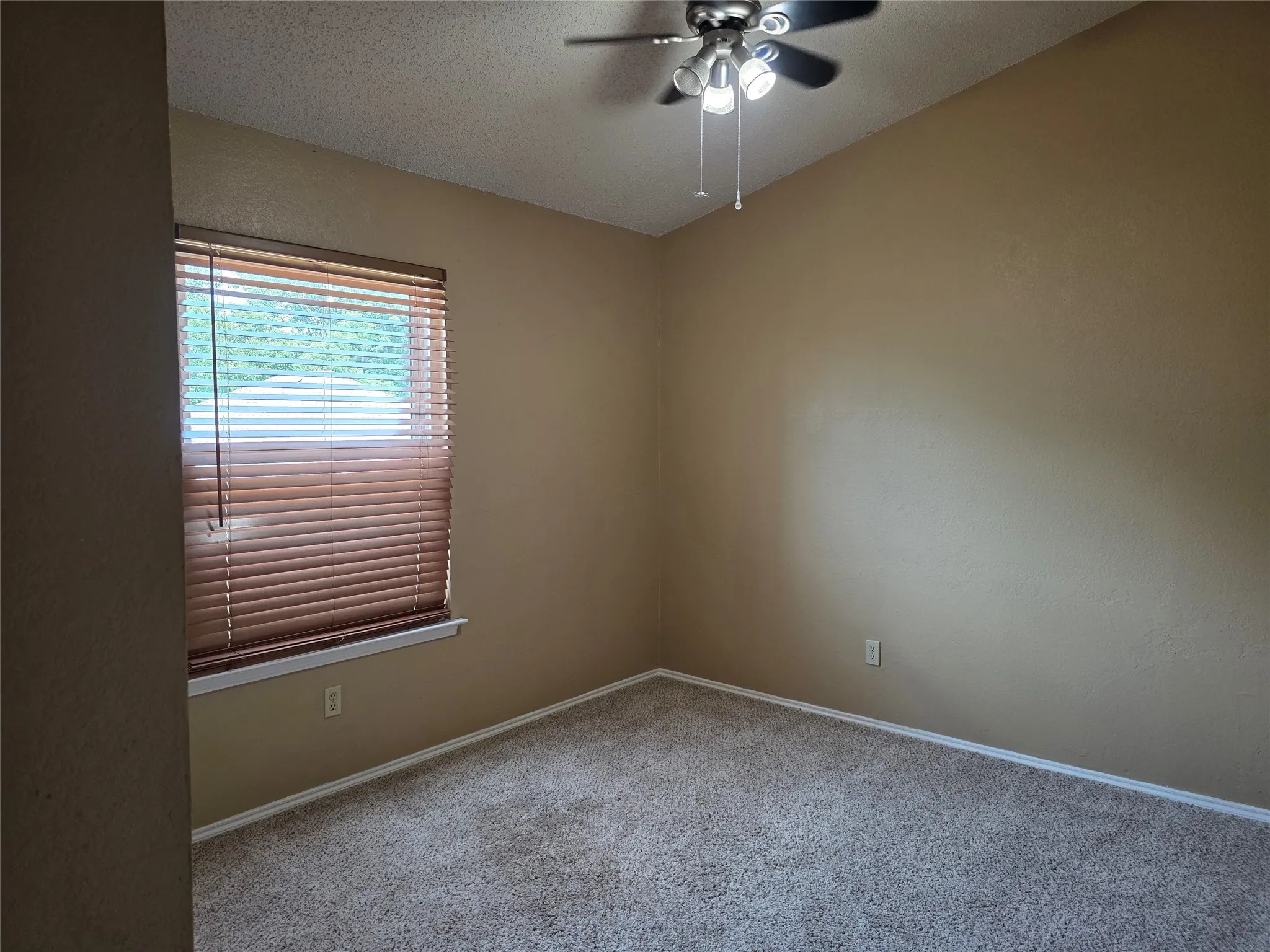 Carpeted room with a window featuring wood-finish blinds, a white window trim, and a ceiling fan with integrated lighting
