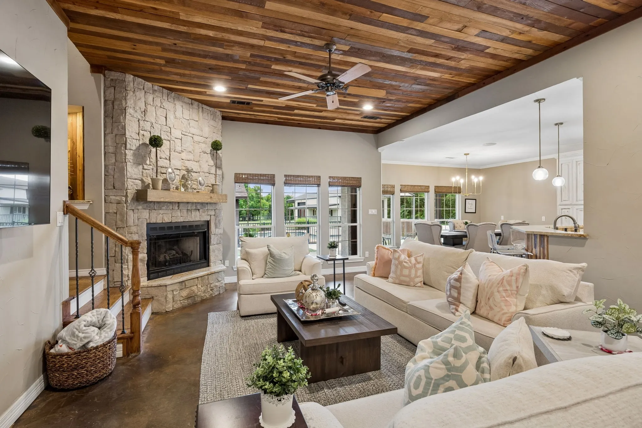 The wood ceiling and stacked stone fireplace give the family room a cozy, rustic charm.
