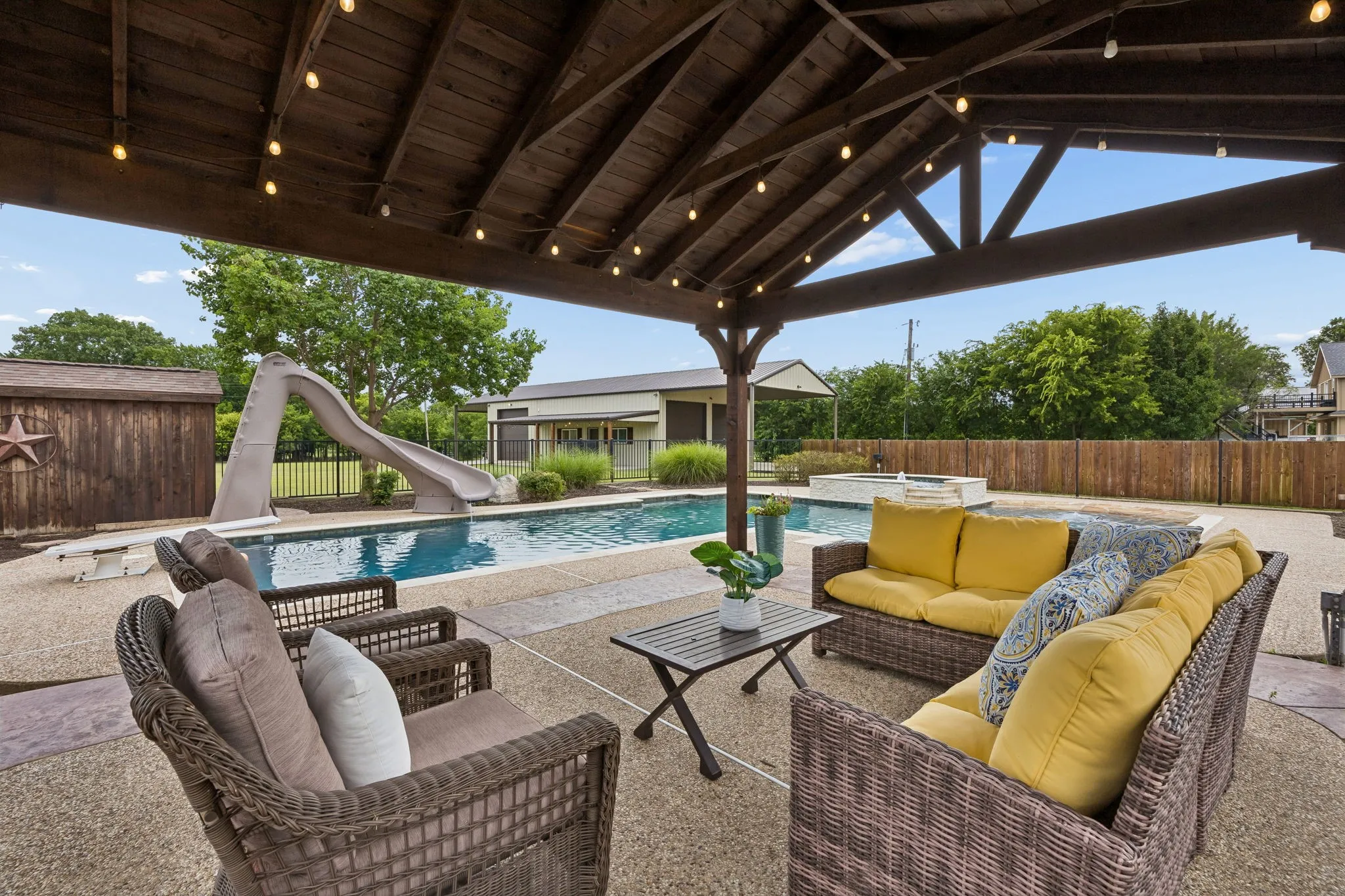 Relax beneath this outdoor living area overlooking the sparking pool. It's such a great pool for all ages with the spa, diving board, and slide!