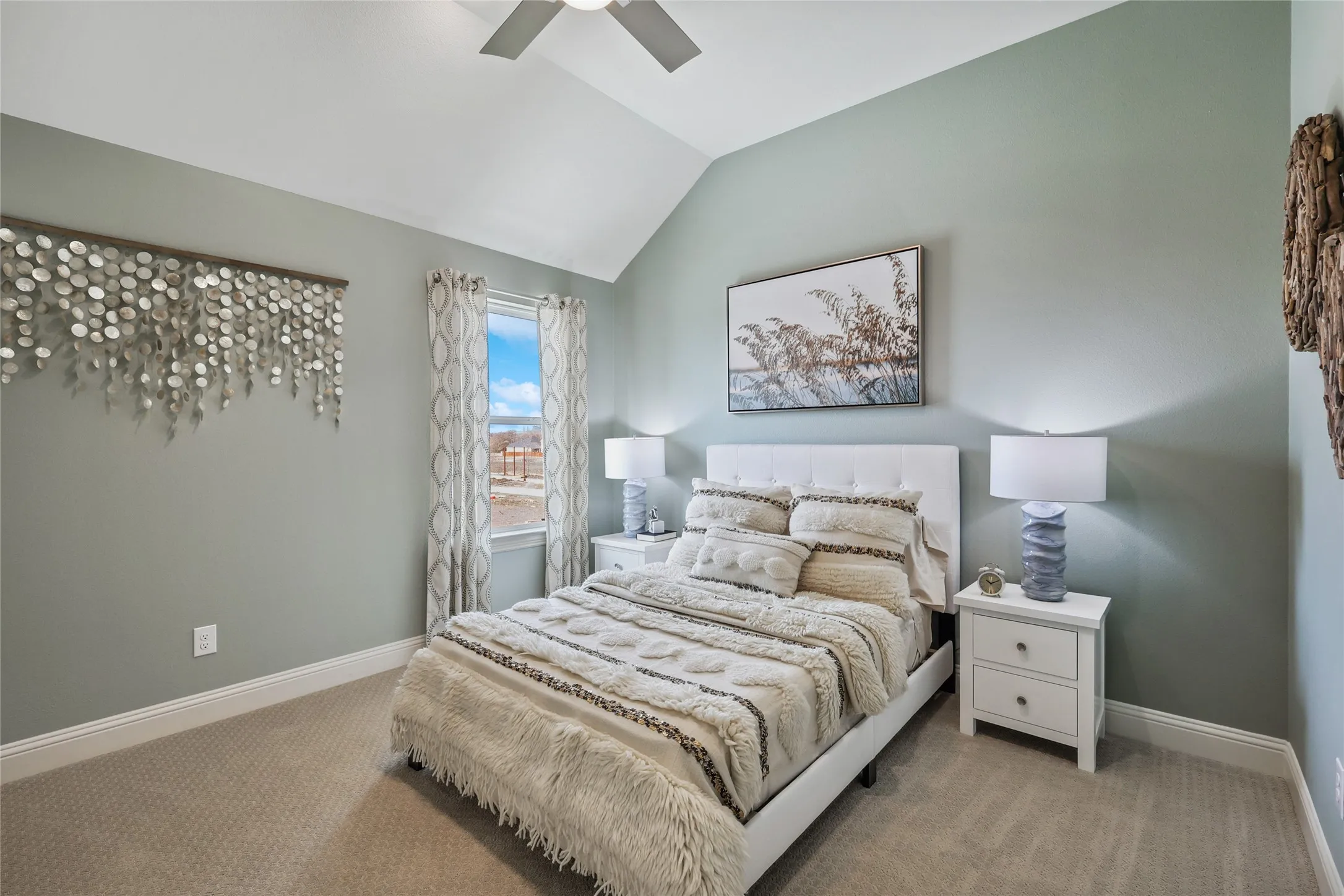 Carpeted room featuring a vaulted ceiling with a ceiling fan, a window with curtains, and two-drawer nightstands