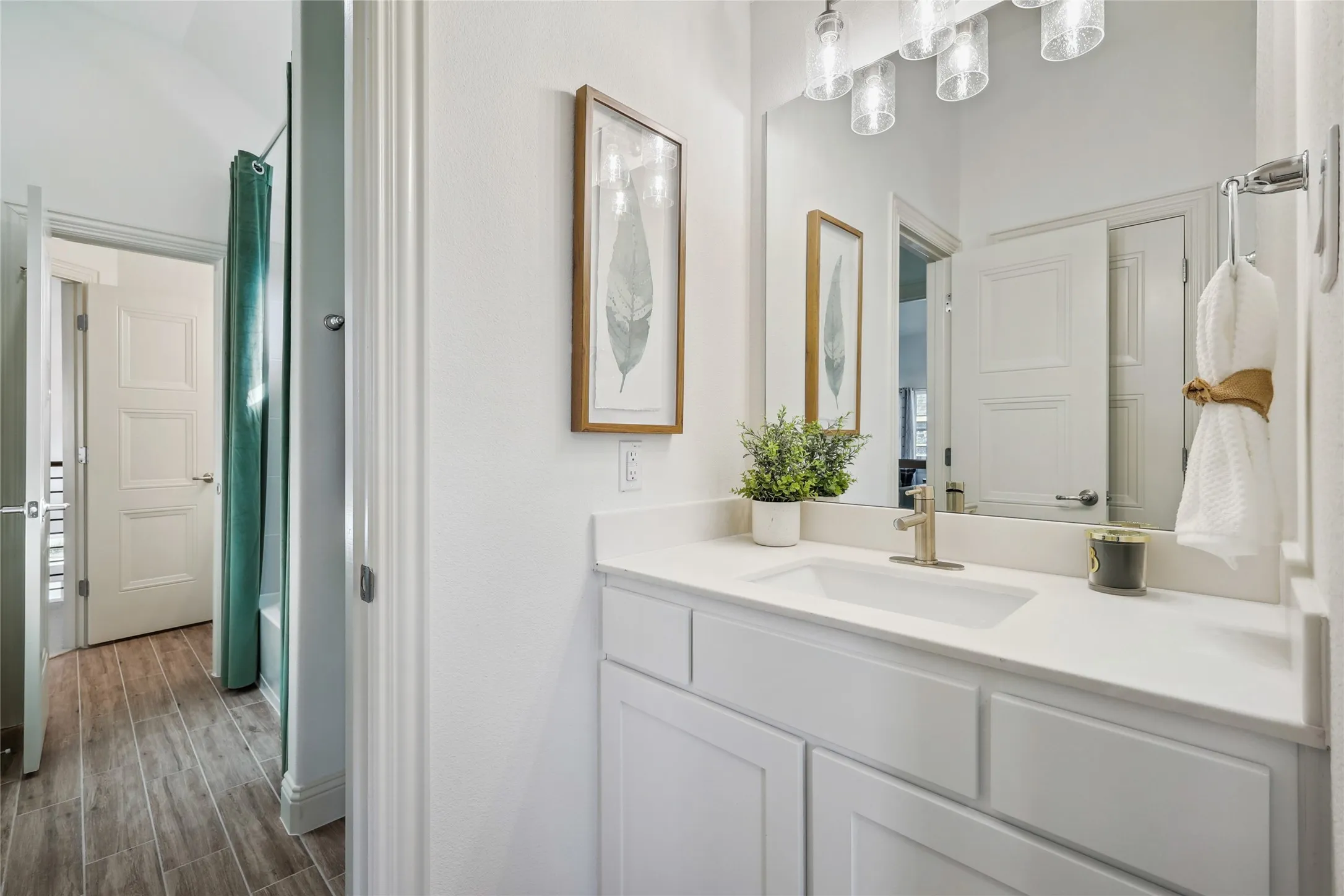 Bathroom vanity with a white countertop and undermount sink, complemented by a contemporary light fixture