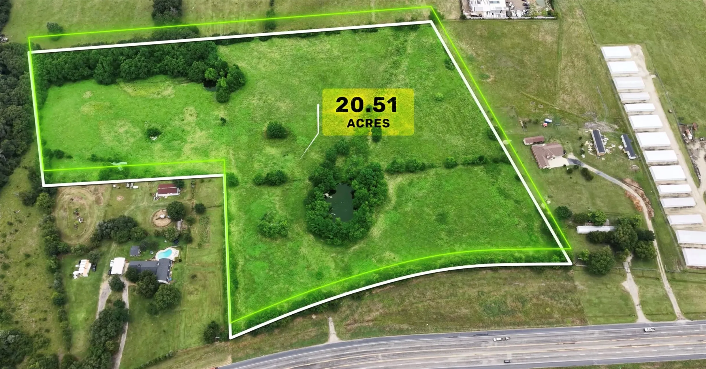 Expansive 20.51-acre parcel featuring green fields, a private pond, and mature tree clusters