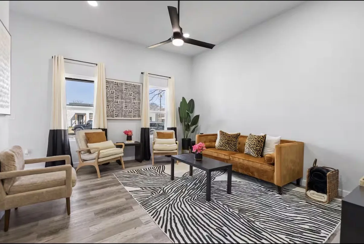 Spacious living area featuring light-toned walls and wood-finish flooring