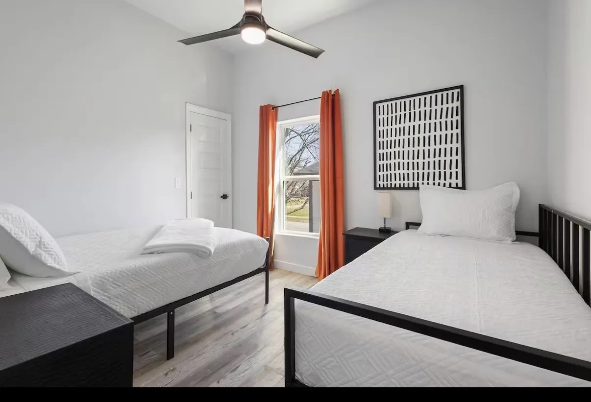 Room featuring wood-finish flooring, a contemporary ceiling fan, and a single window with orange drapes