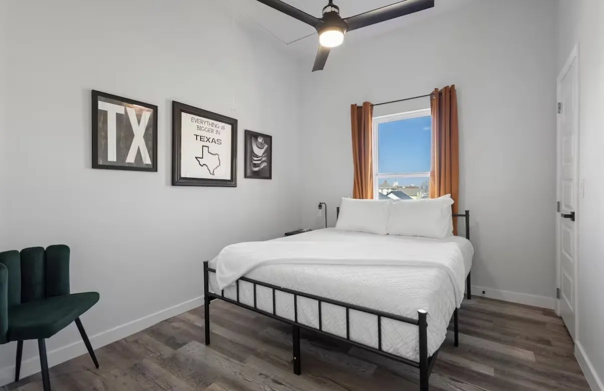 Vaulted ceiling with a black ceiling fan, wood-finish flooring, and a window with natural light