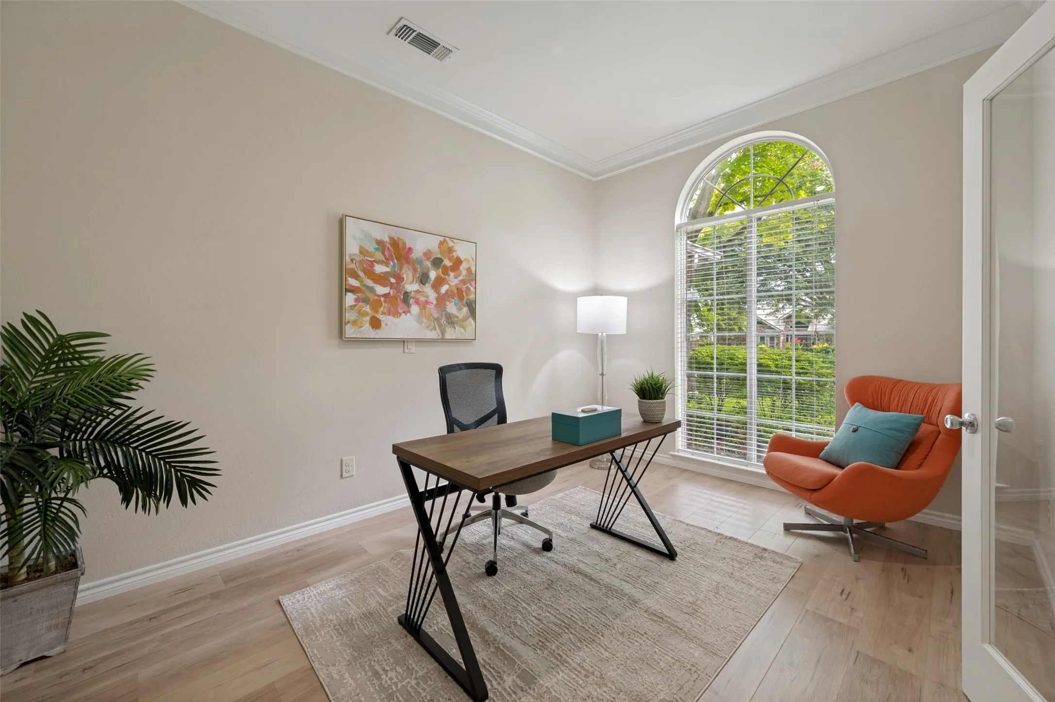 Room featuring an arched window, crown molding, and wood-finish flooring