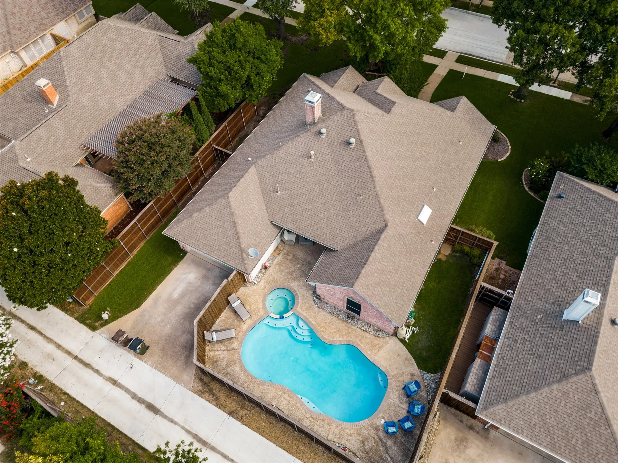 Residential property featuring a freeform swimming pool with integrated spa, a concrete pool deck, and a fenced backyard