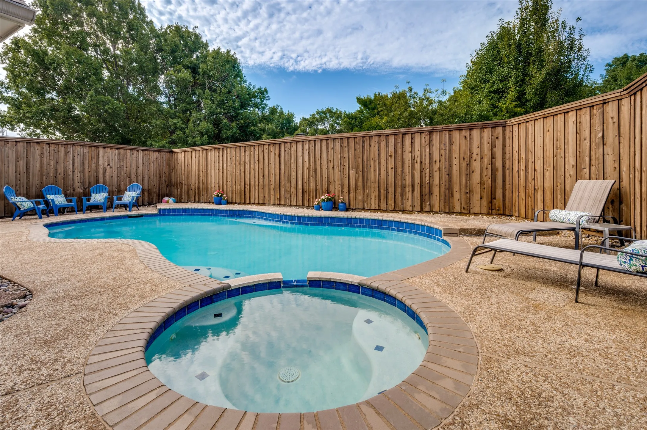 Private backyard featuring a freeform swimming pool and integrated spa