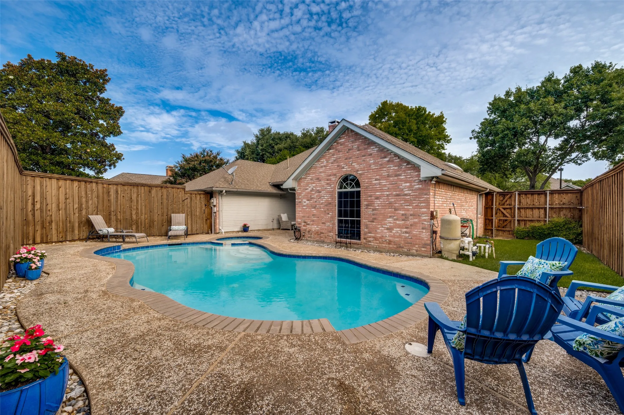 Freeform swimming pool with integrated spa and a textured concrete surround