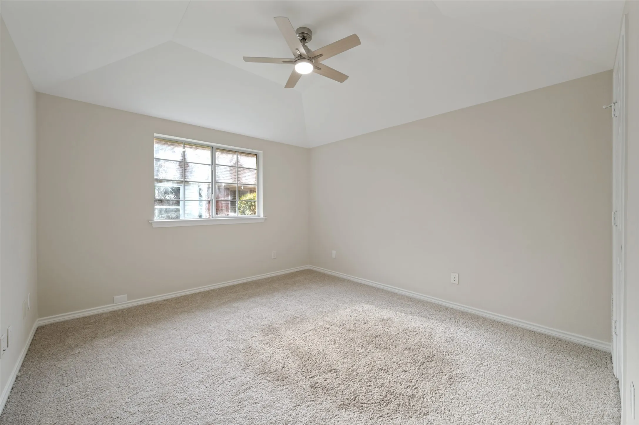 Spacious room featuring heightened ceilings, a contemporary ceiling fan with integrated lighting, neutral-toned walls, and plush carpeting