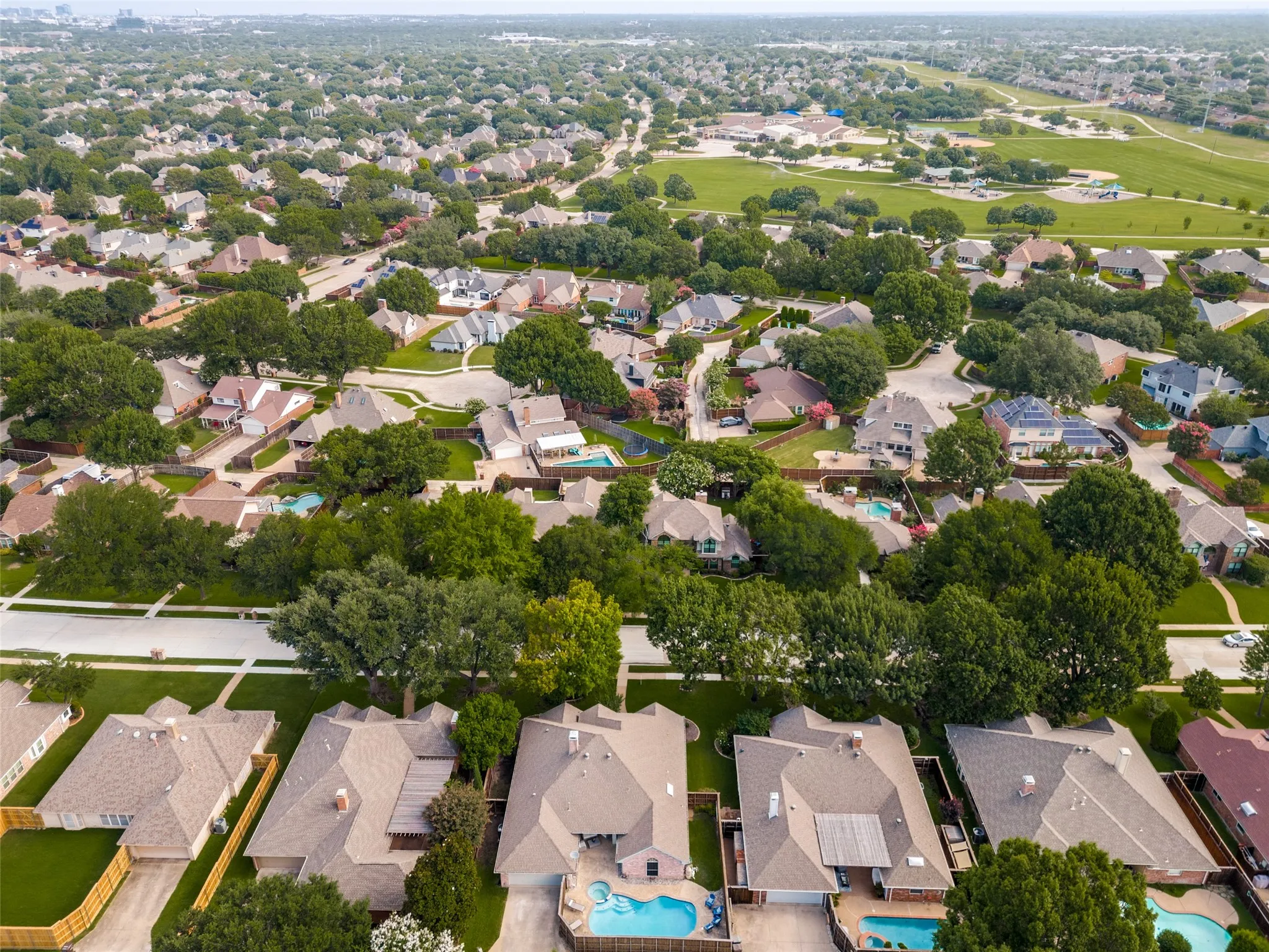 Aerial perspective showcasing a residential neighborhood with numerous single-story and two-story homes featuring varying rooflines and exterior finishes
