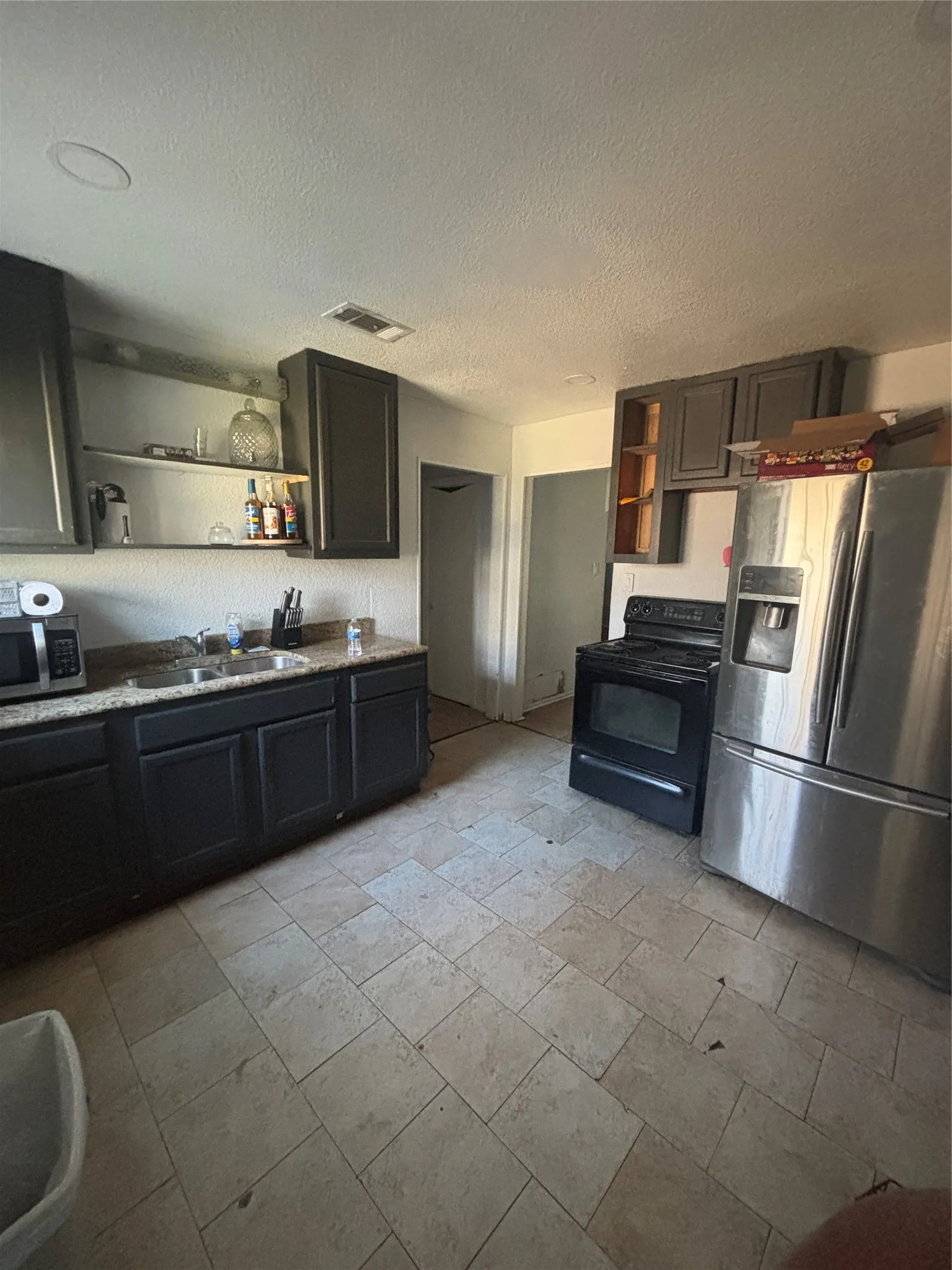 Kitchen featuring tile flooring, dark cabinetry, and light-colored countertops