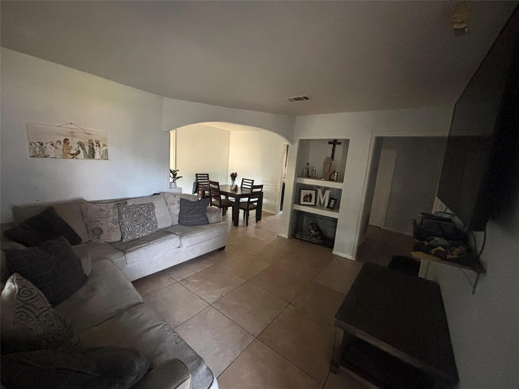 Spacious living area featuring tile flooring, an arched entryway, and built-in shelving