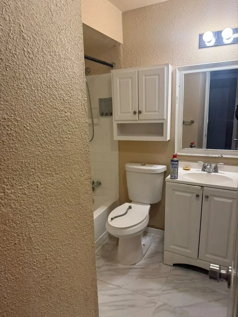 Bathroom featuring a white vanity with under-sink storage, a mirror, overhead vanity lighting, and a white toilet