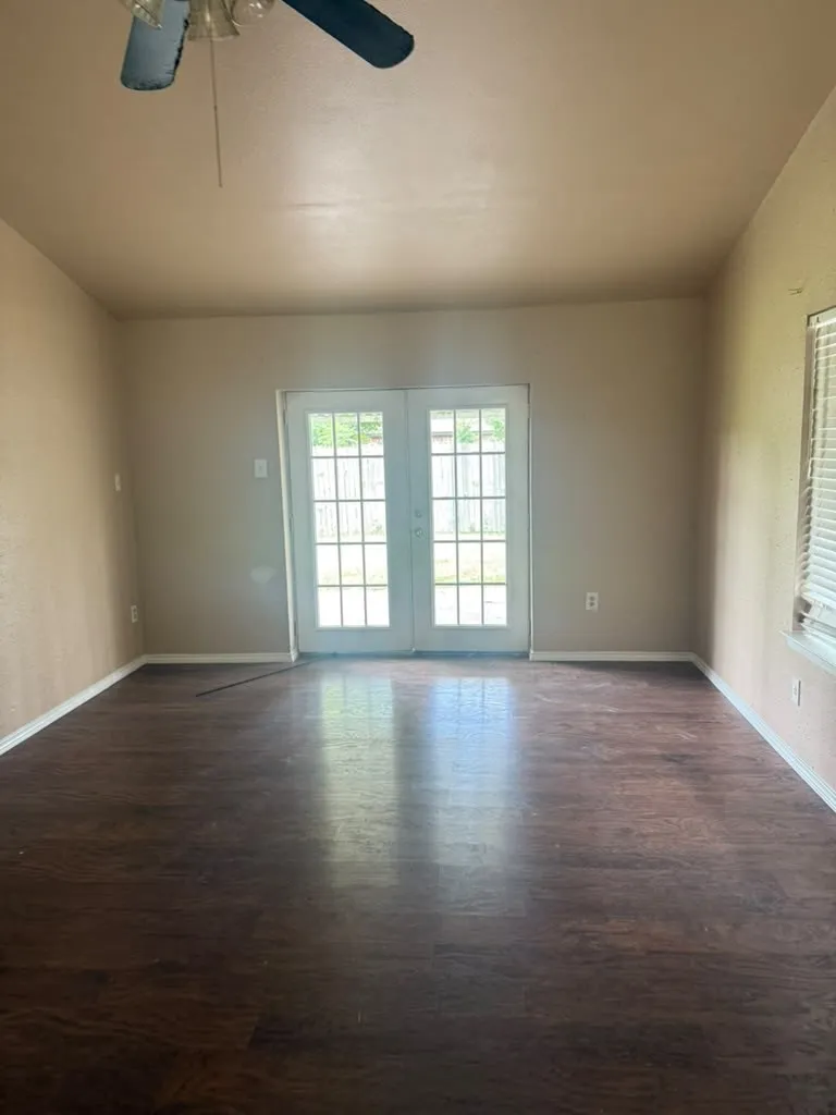 Spacious room featuring wood-finish flooring, white baseboards, and neutral wall tones