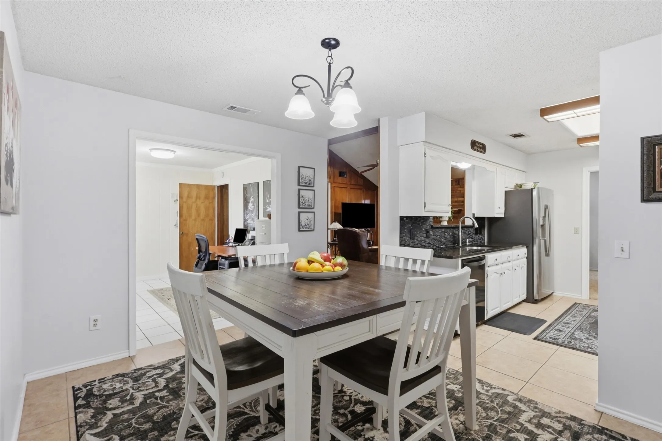 Dining area featuring a contemporary chandelier, tile flooring, and a decorative area rug