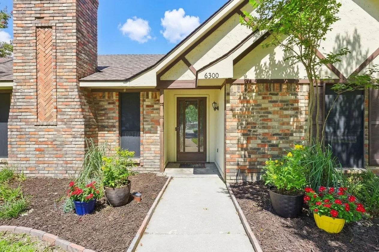 Brick and stucco exterior featuring a prominent chimney with herringbone detailing