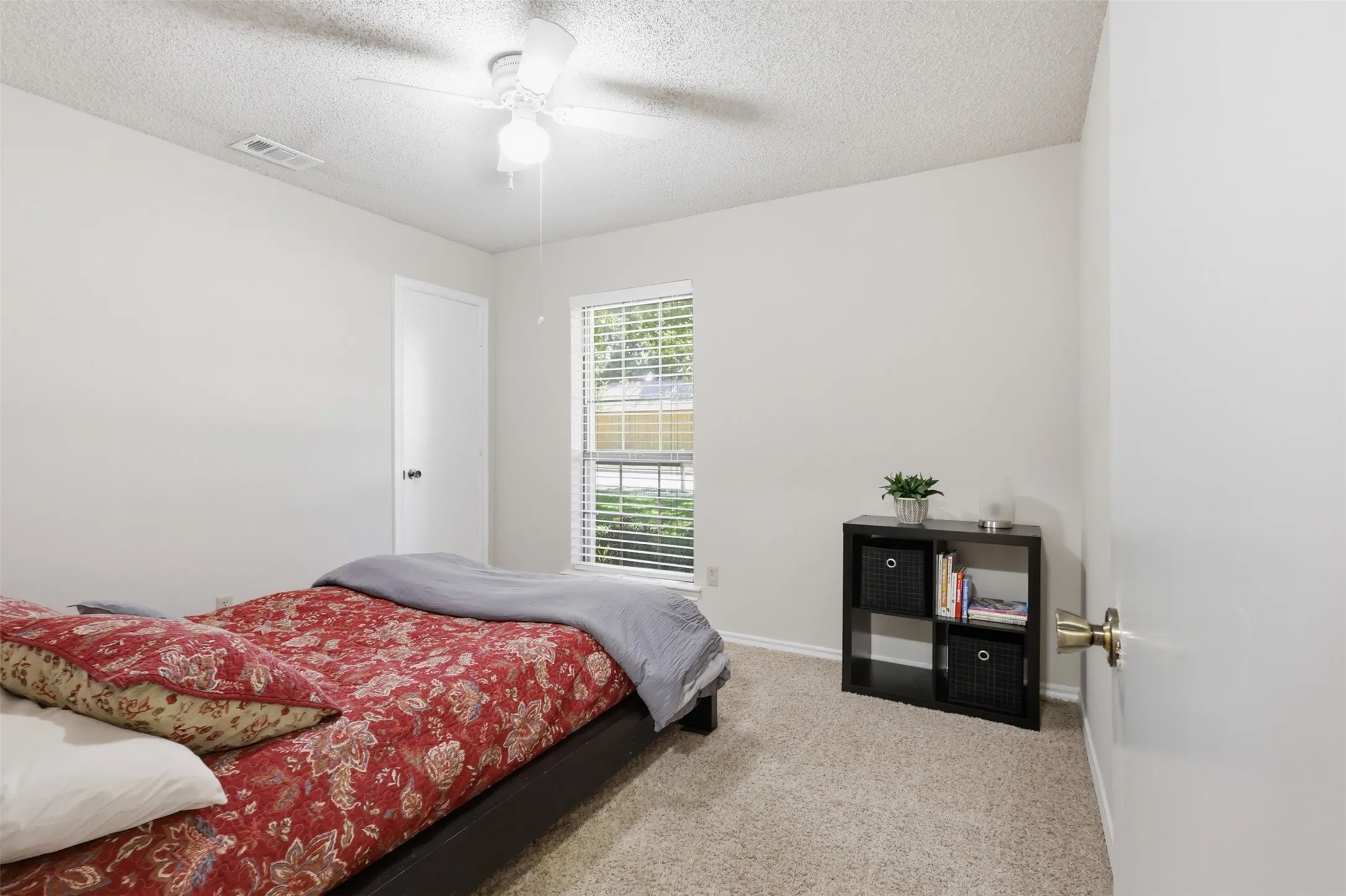 Carpeted room with a ceiling fan, white walls, and a window featuring horizontal blinds