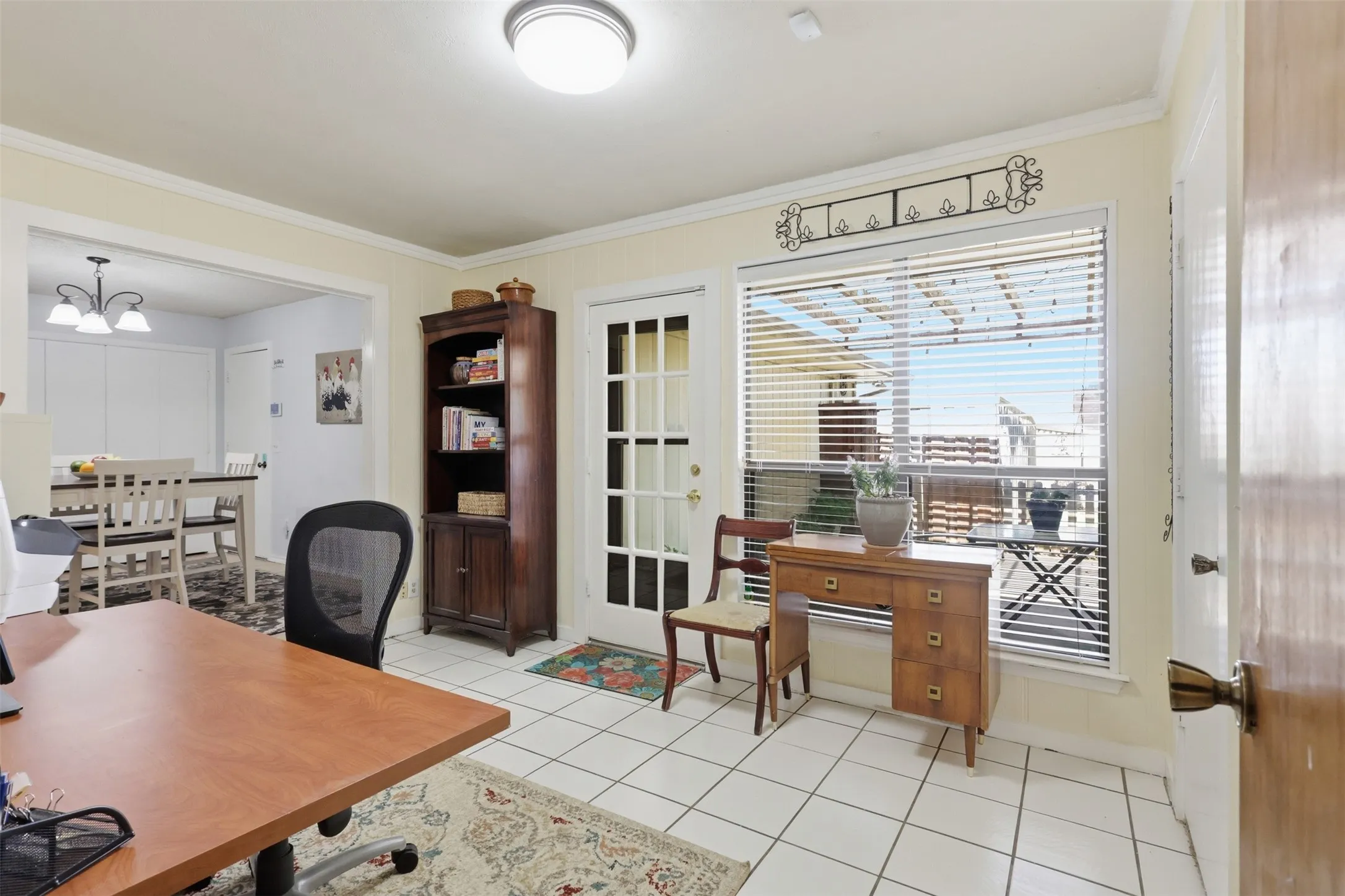 Bright room featuring white tile flooring and a patio door with integrated blinds