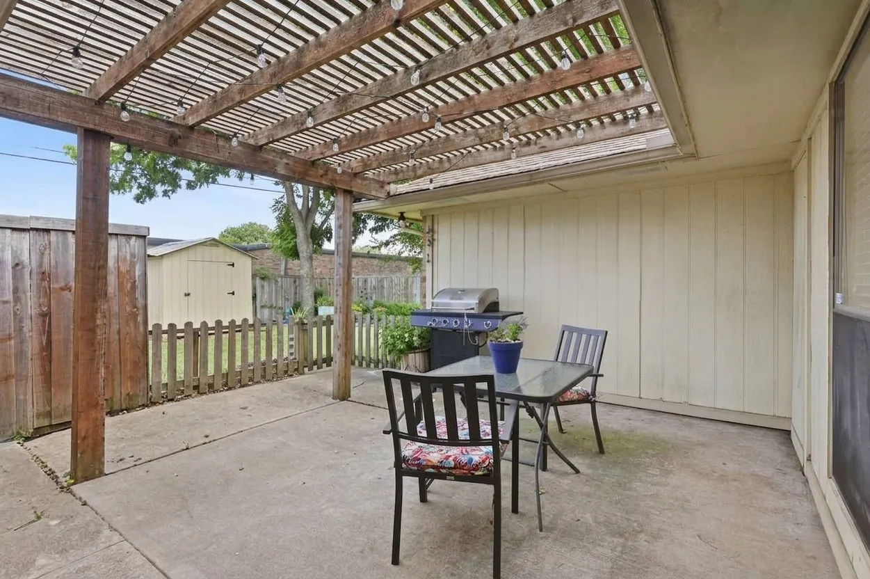 Concrete patio featuring a wooden pergola with string lighting
