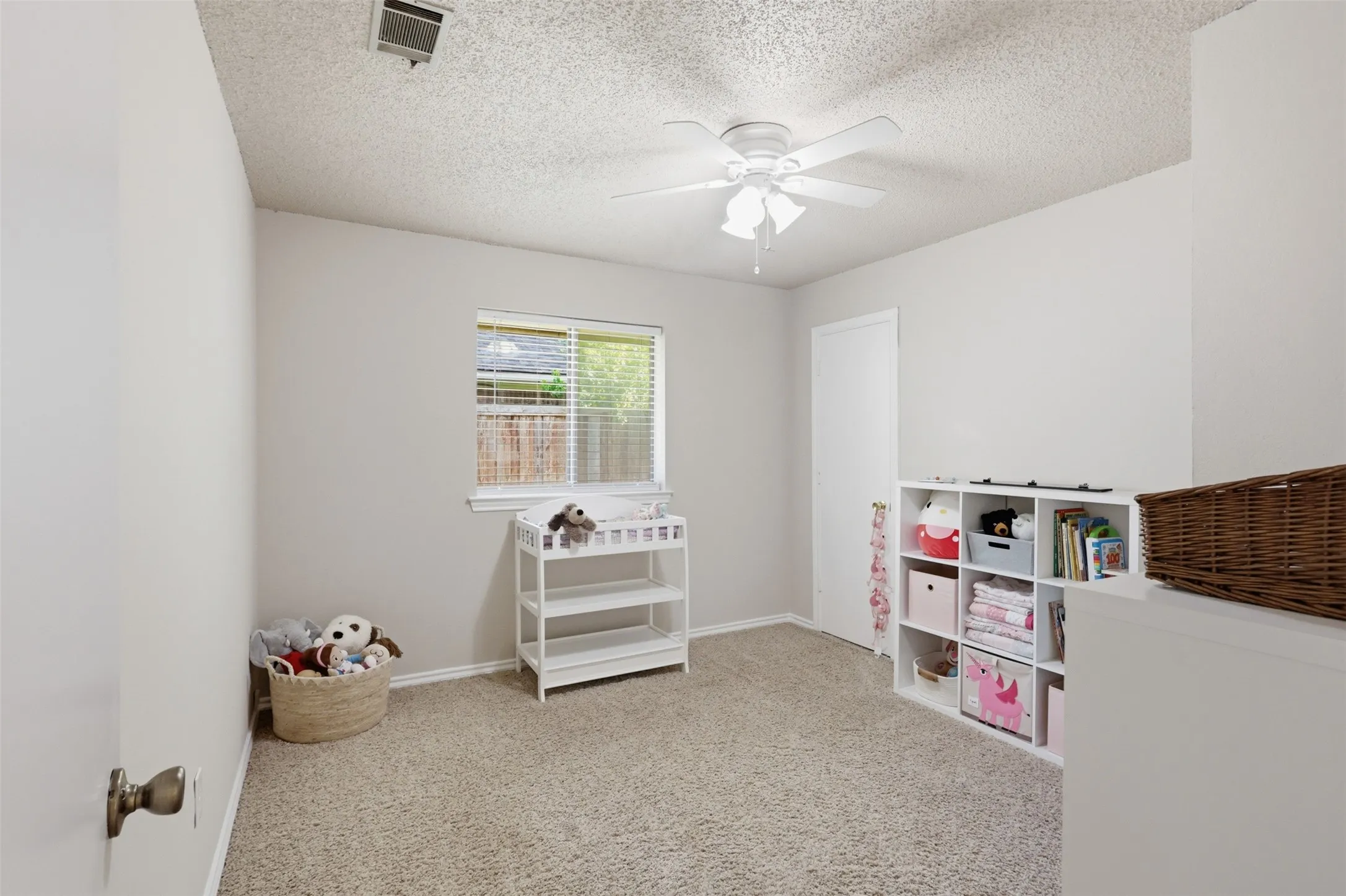 Neutral-toned room with plush carpeting and a textured ceiling