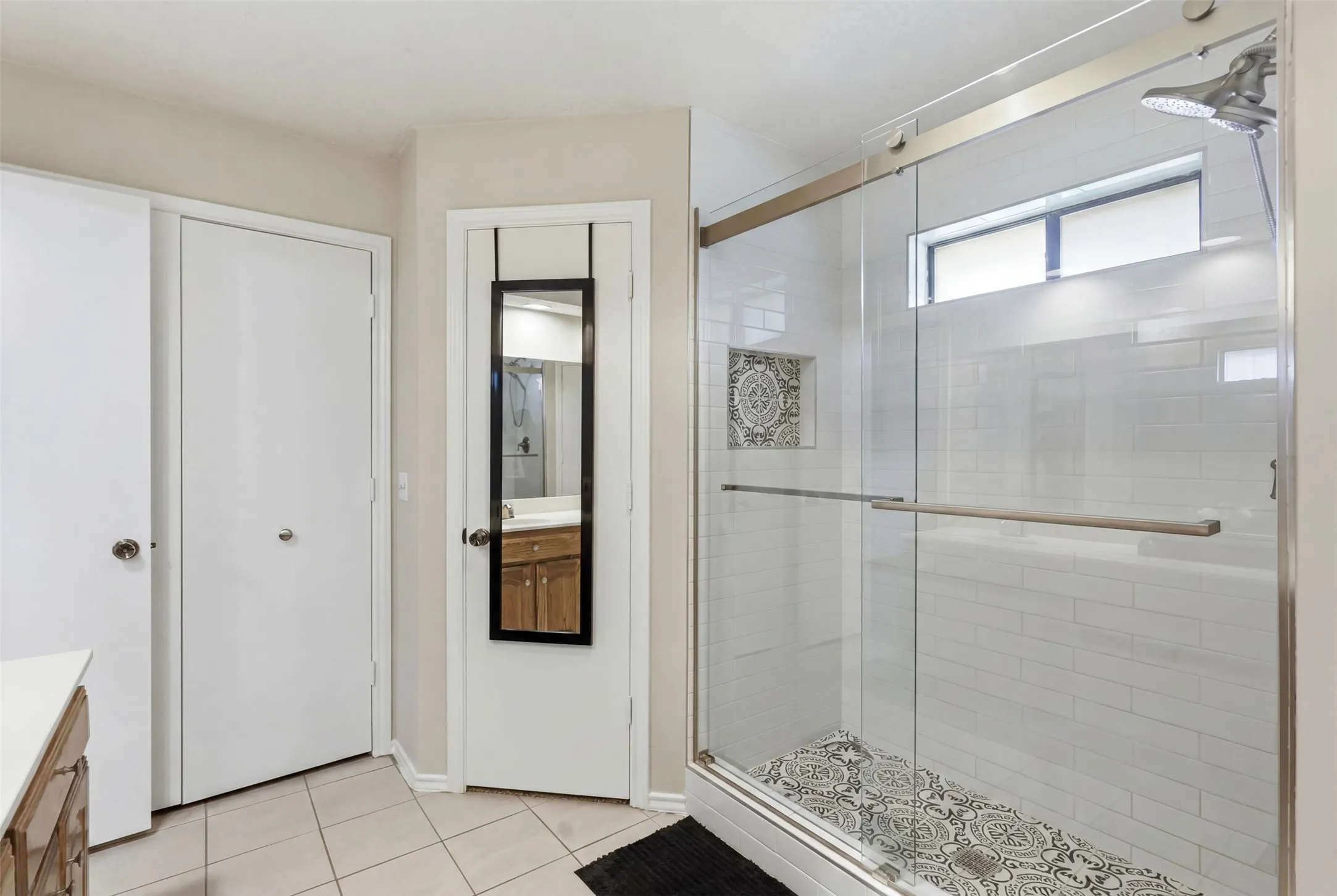Glass-enclosed shower featuring subway tile walls and a decorative tile floor