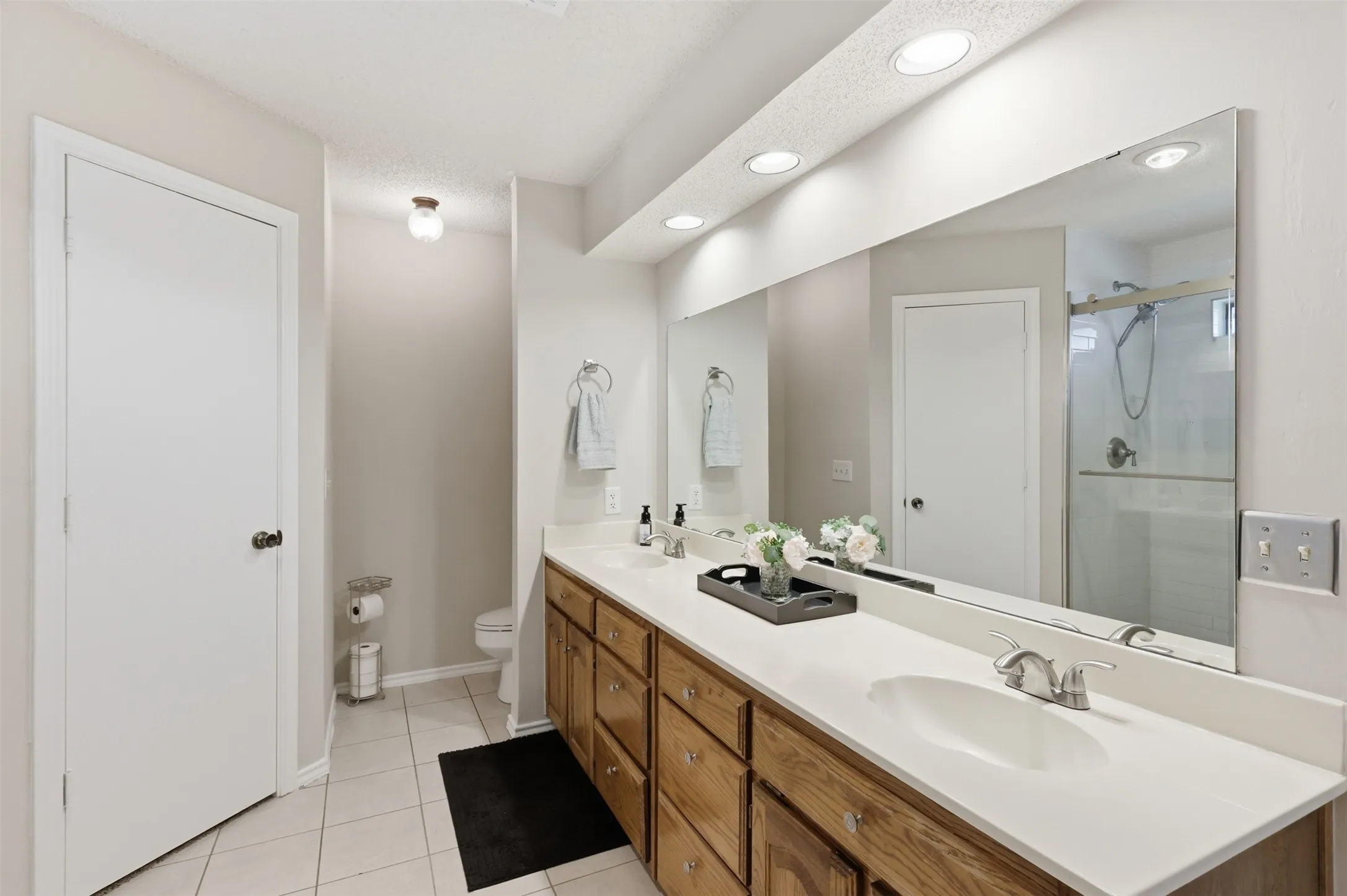 Spacious bathroom featuring a dual vanity with wood cabinetry, light-colored countertops, and integrated sinks