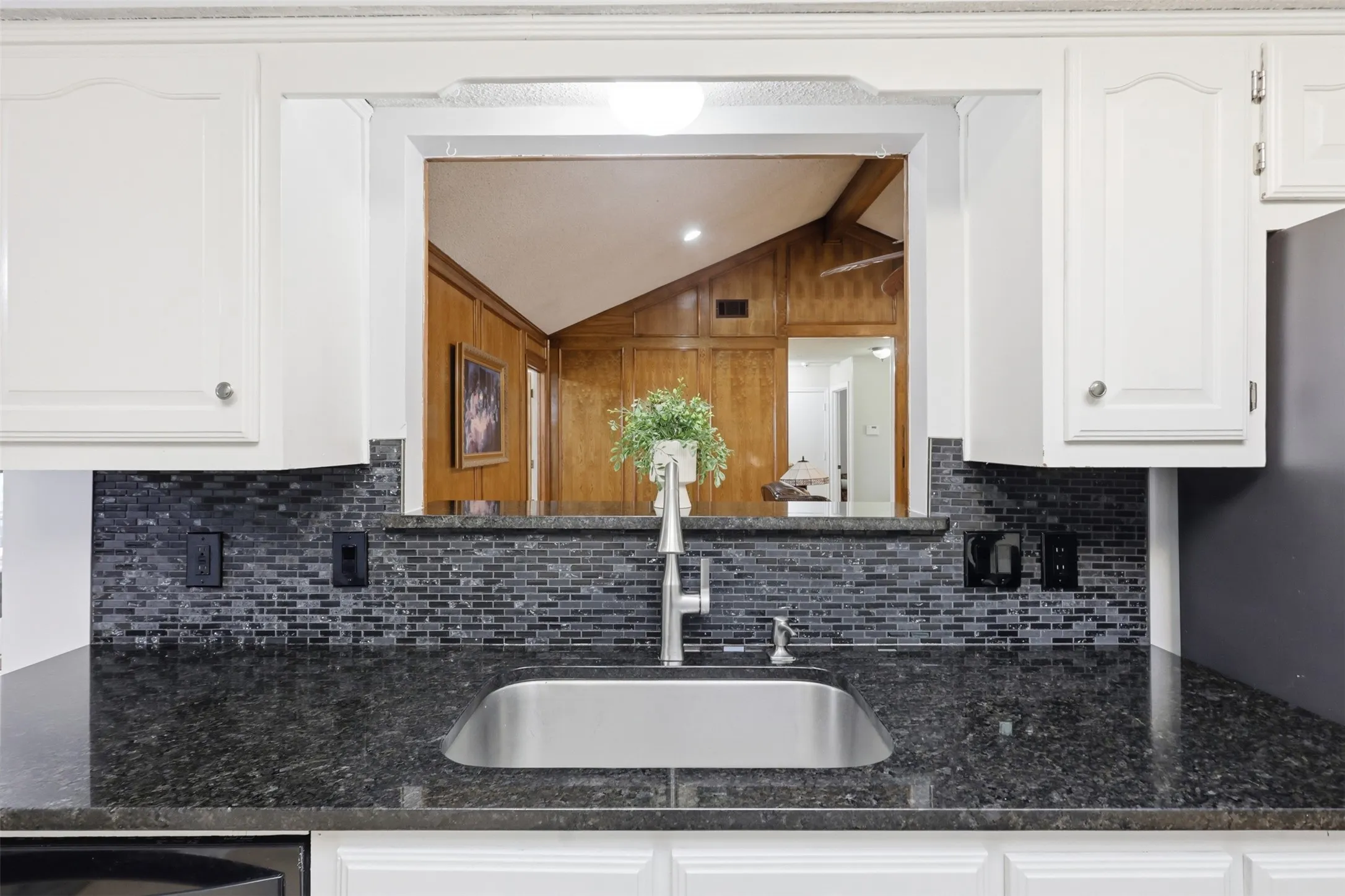 Kitchen featuring white cabinetry, dark speckled countertops, and a gray subway tile backsplash