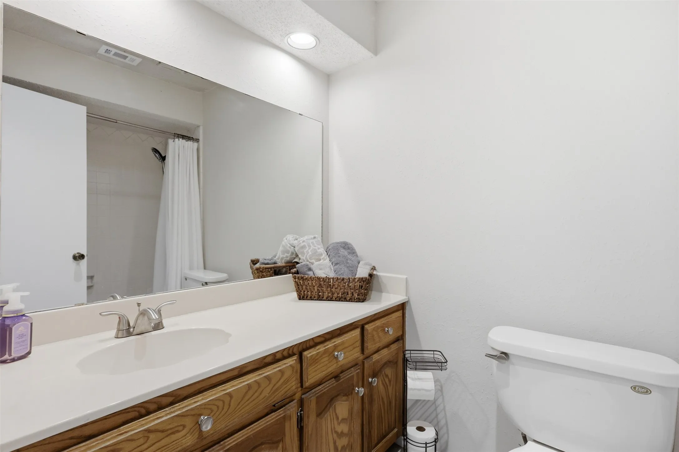 Bathroom featuring a vanity with wood cabinetry, light-toned countertop, and integrated sink