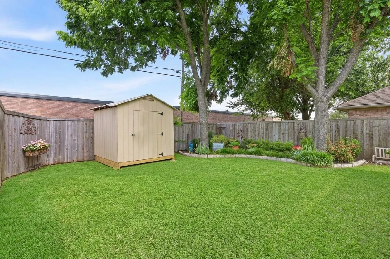 Expansive backyard featuring a manicured lawn, established trees, and a privacy fence