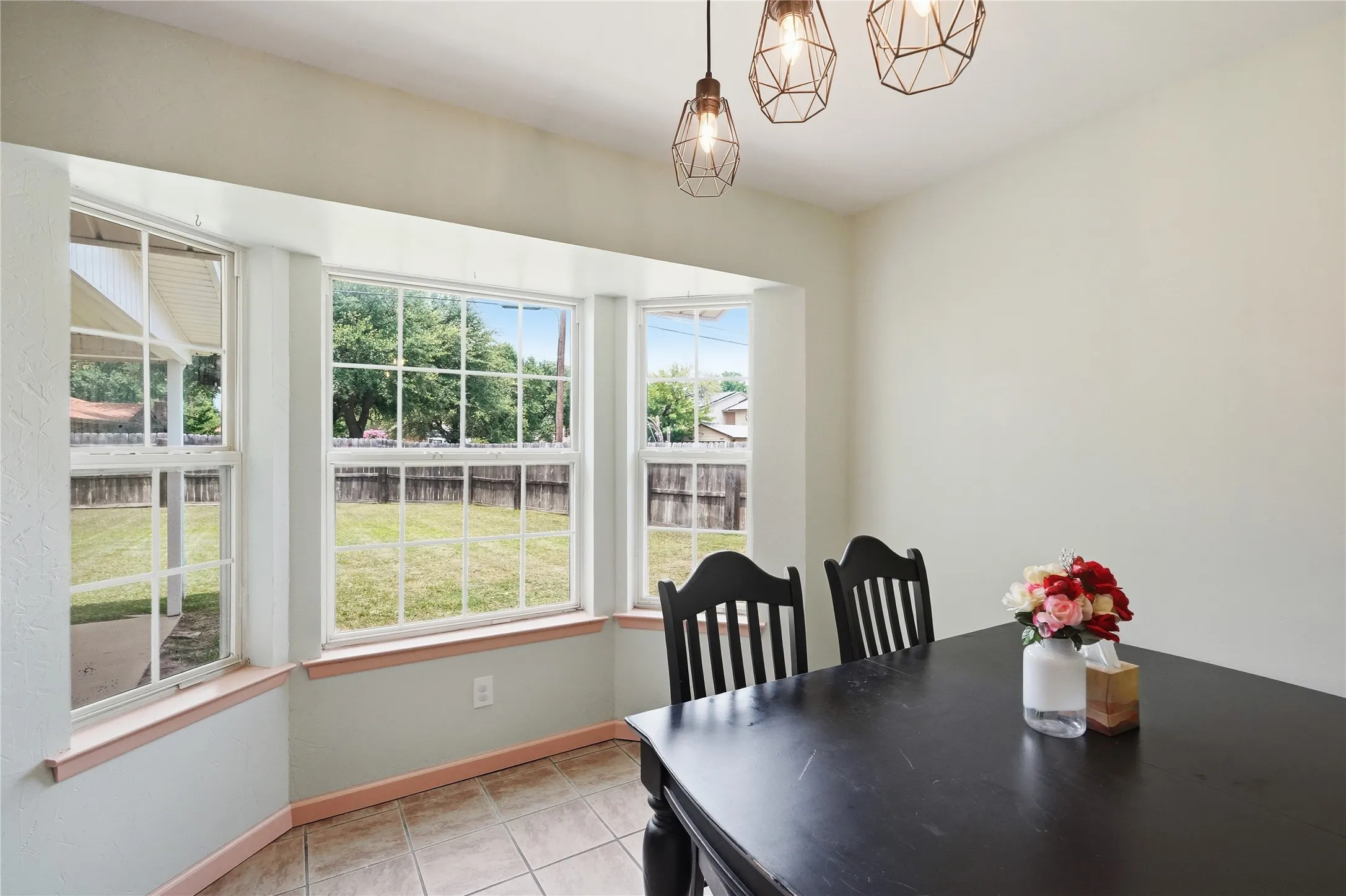 Dining area featuring a bay window with multiple panes, tile flooring, and three geometric pendant light fixtures