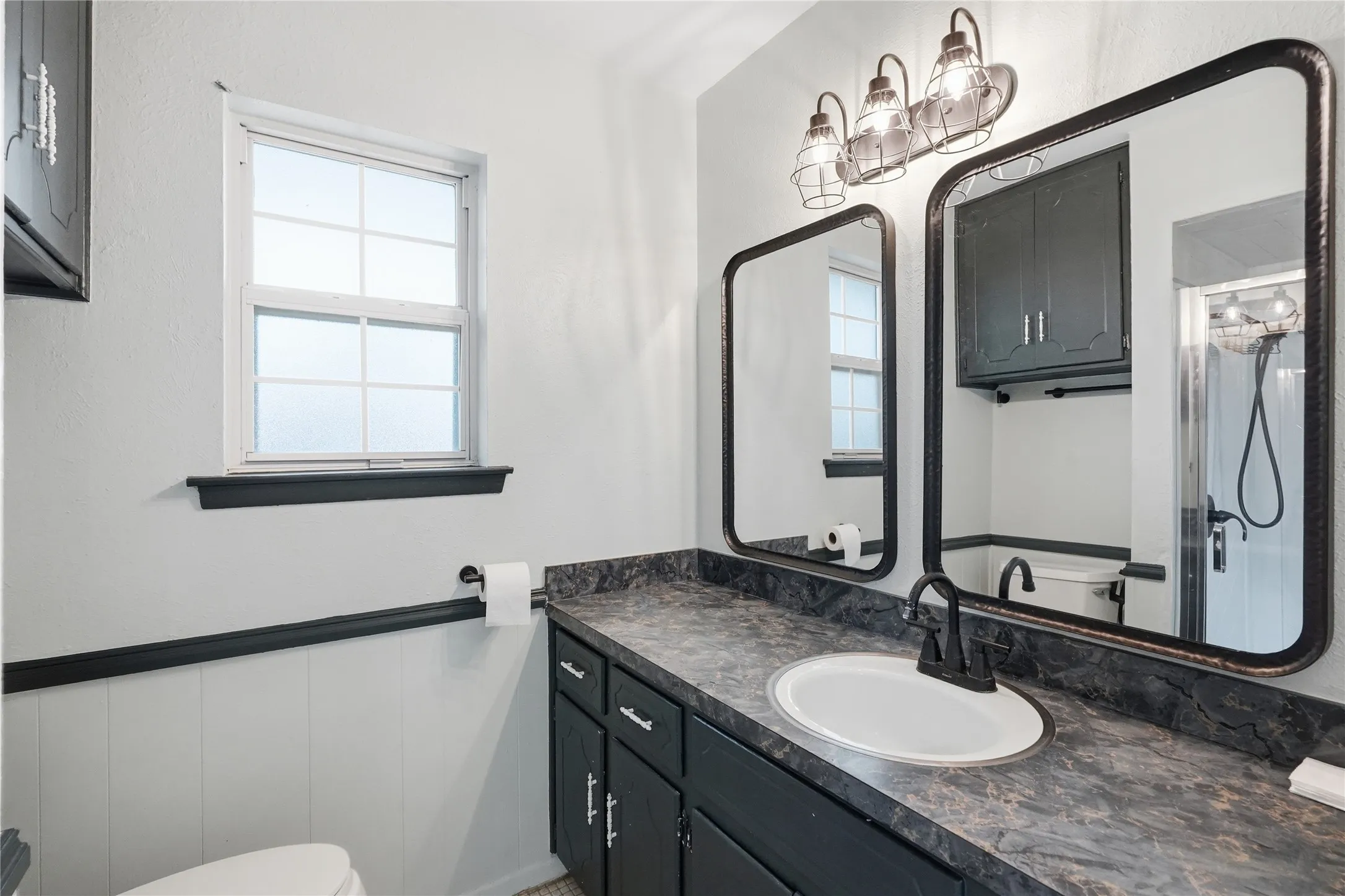 Vanity area featuring a dark countertop, an oval undermount sink, and a matte black single-handle faucet