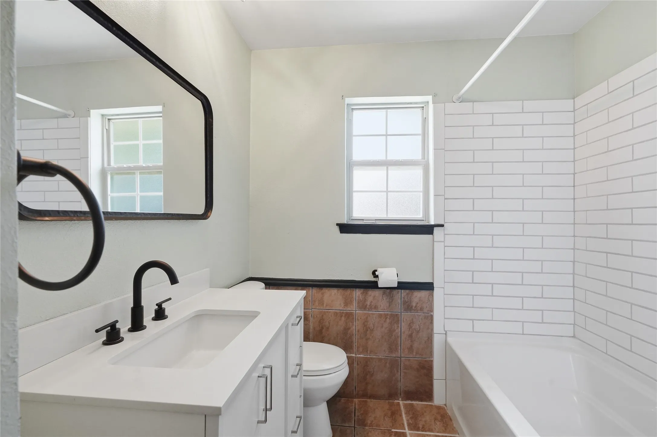 Bathroom featuring a white vanity with integrated sink, matte black faucet, and white countertop