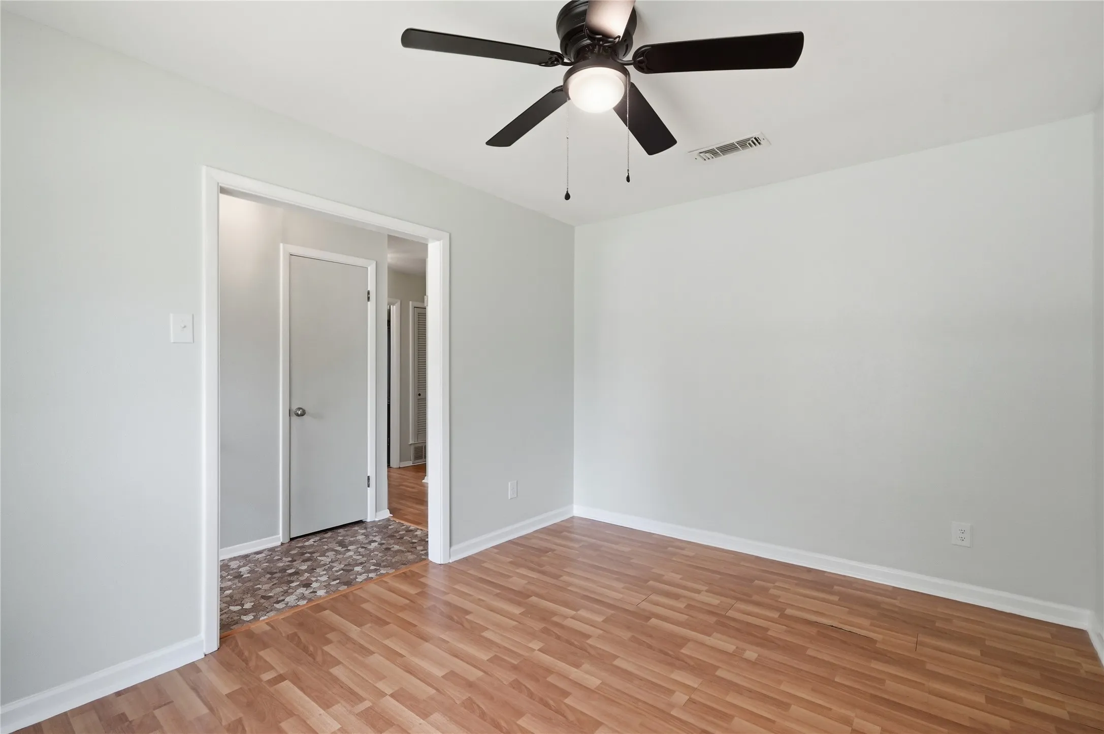 Room featuring wood-finish flooring, light-toned wall paint, and a ceiling fan with integrated lighting