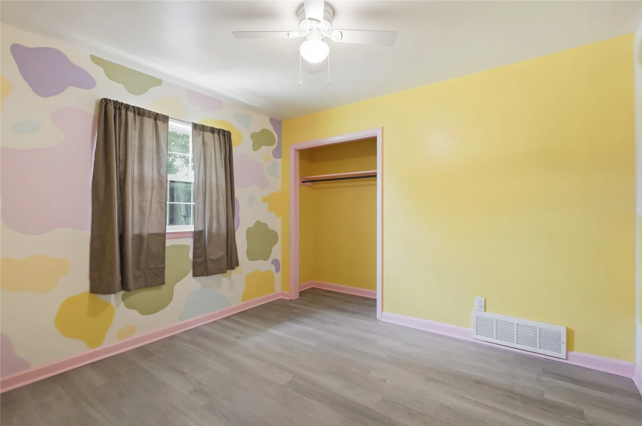 Room featuring wood-finish flooring, a ceiling fan, and a built-in closet with hanging rod