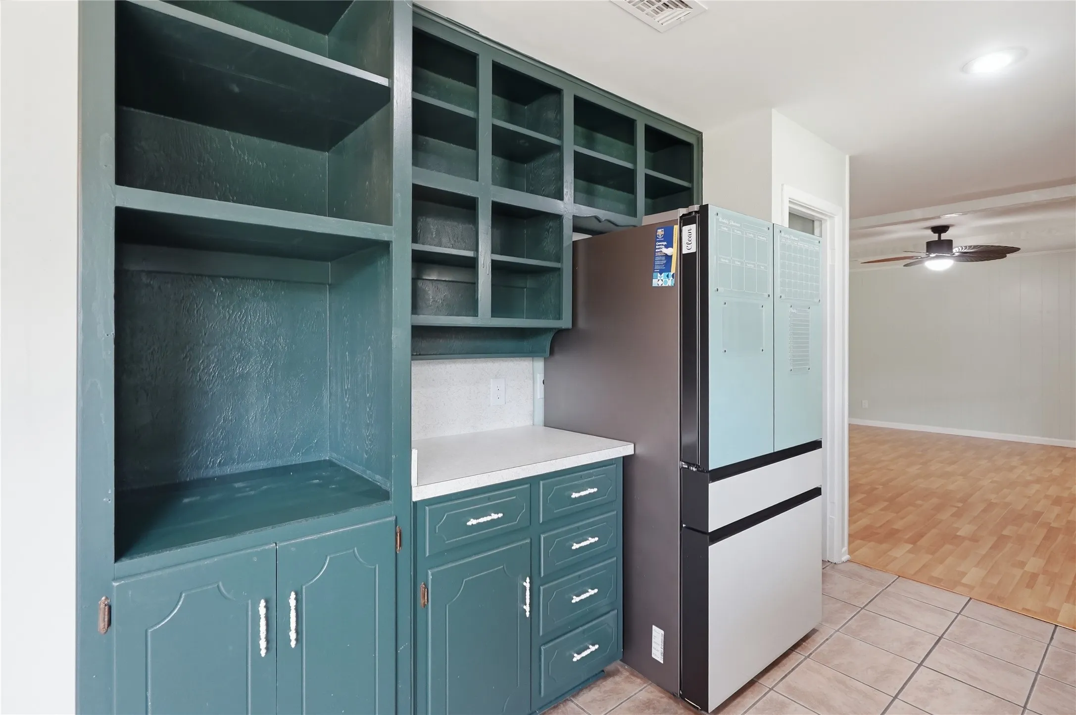 Built-in cabinetry in a deep teal finish, featuring open shelving, enclosed storage, and a white countertop