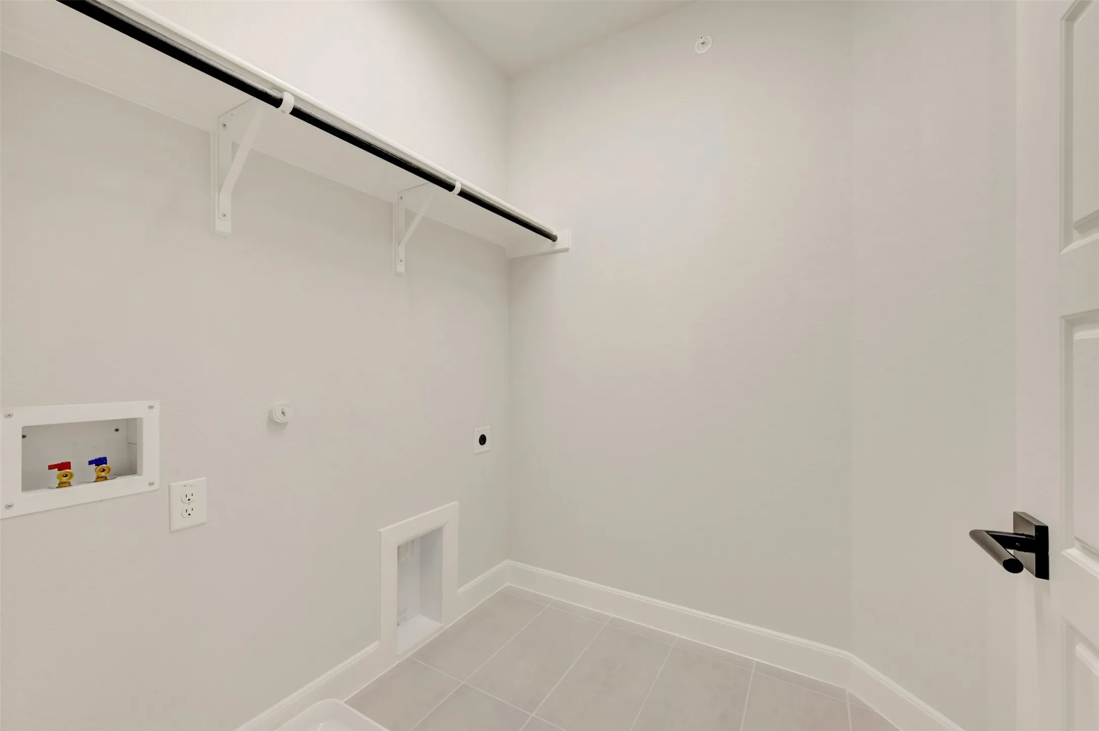 Light gray wall paint with white trim, ceramic tile flooring, and a built-in shelf with hanging rod