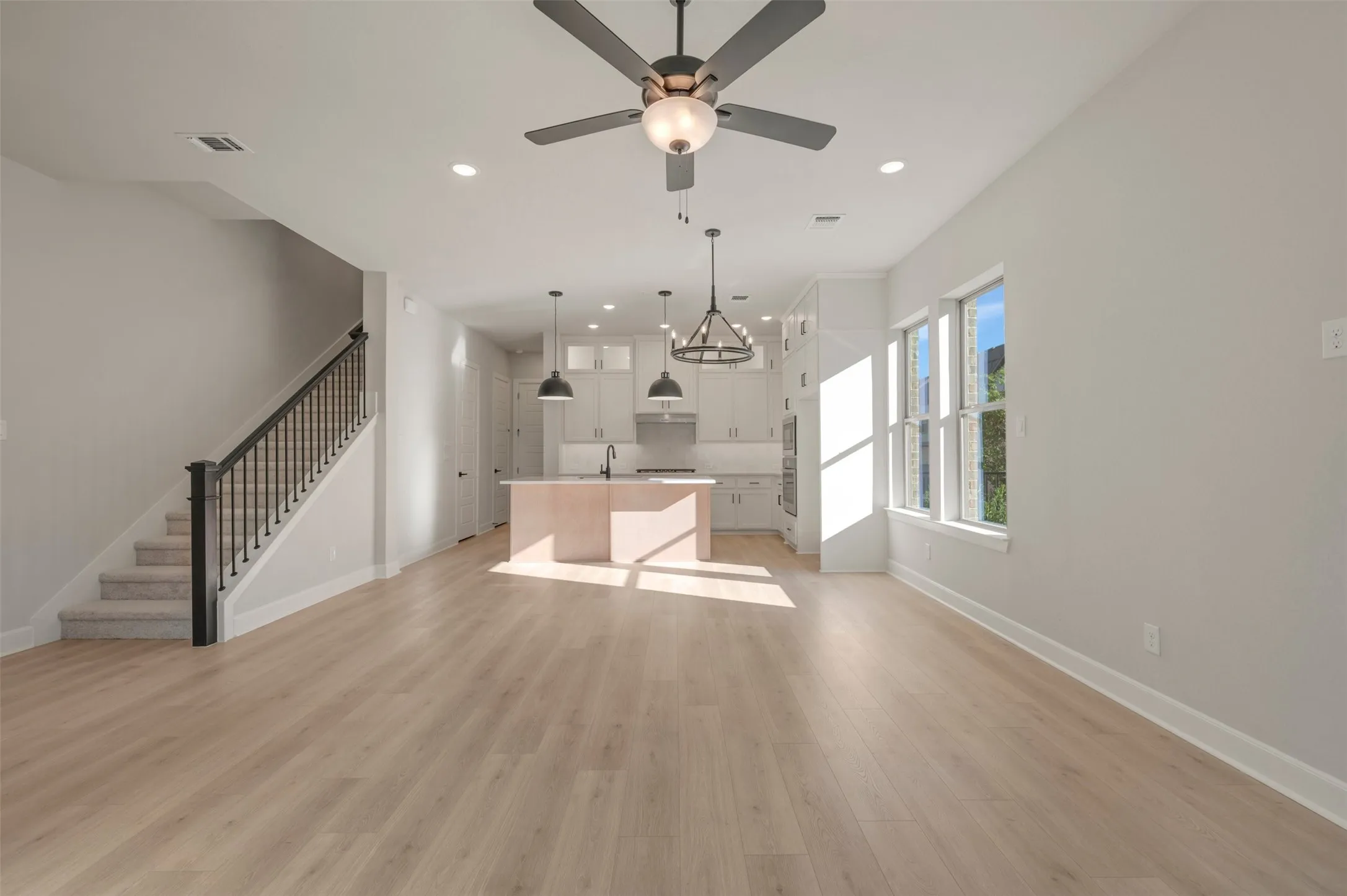 Open-concept living space featuring wood-finish flooring, a contemporary ceiling fan, and recessed lighting