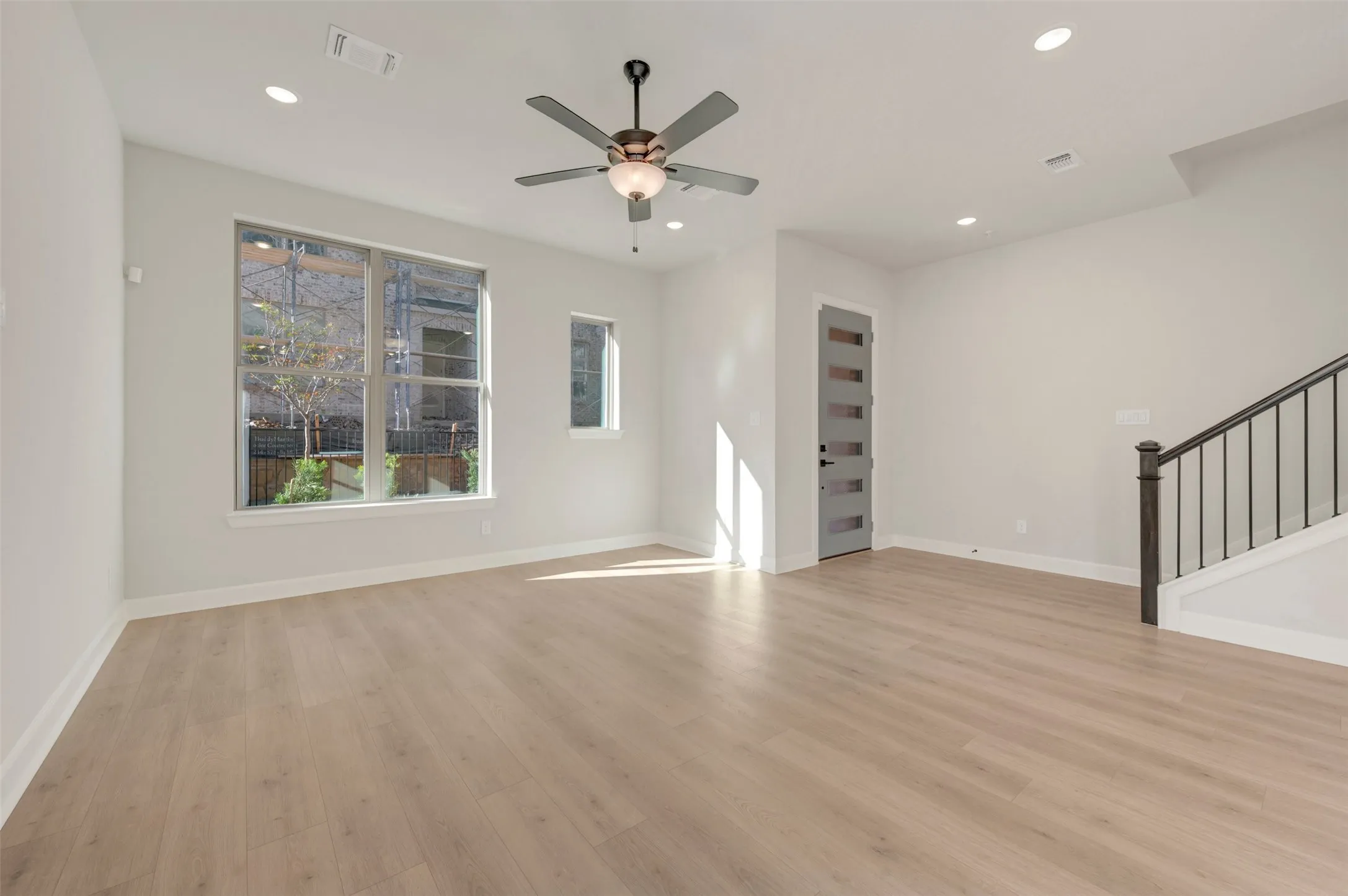Recessed lighting, light wood-finish flooring, a contemporary ceiling fan, and multiple windows