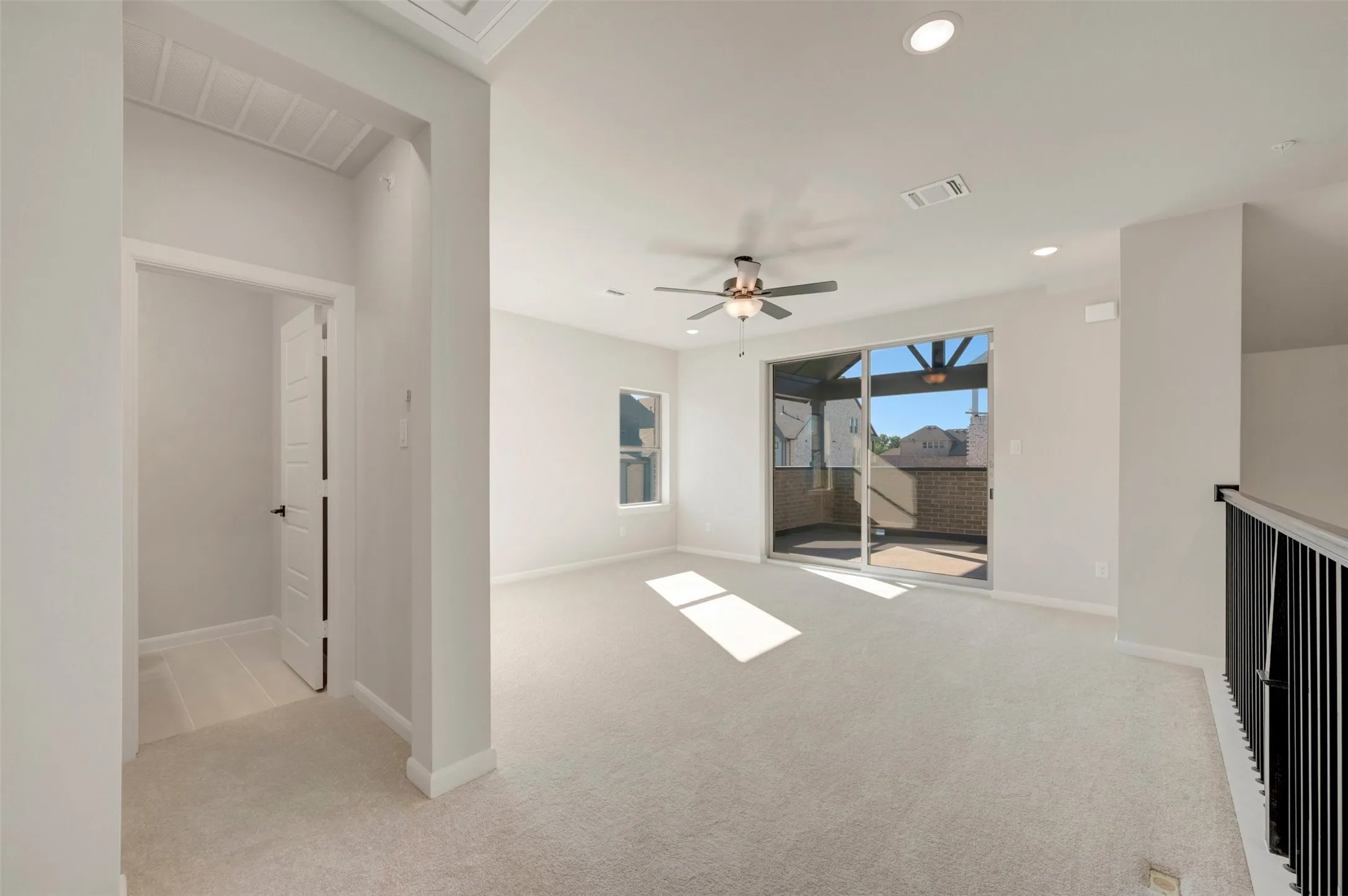 Open recreational space featuring neutral carpeting, a ceiling fan, recessed lighting, and sliding glass doors that open to an outdoor balcony