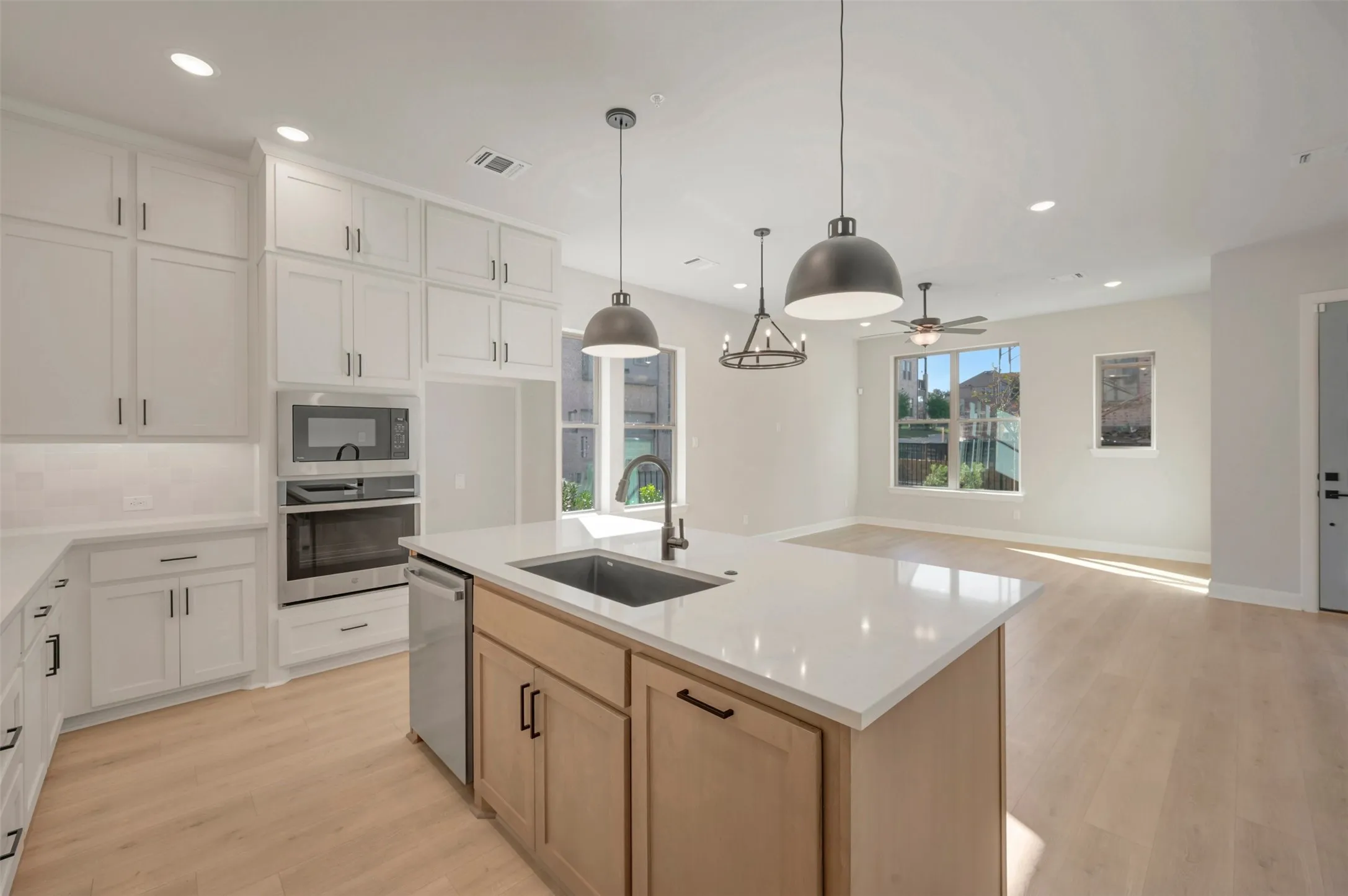 Kitchen featuring white cabinetry, wood-finish flooring, recessed lighting, and a kitchen island with a built-in sink and dishwasher