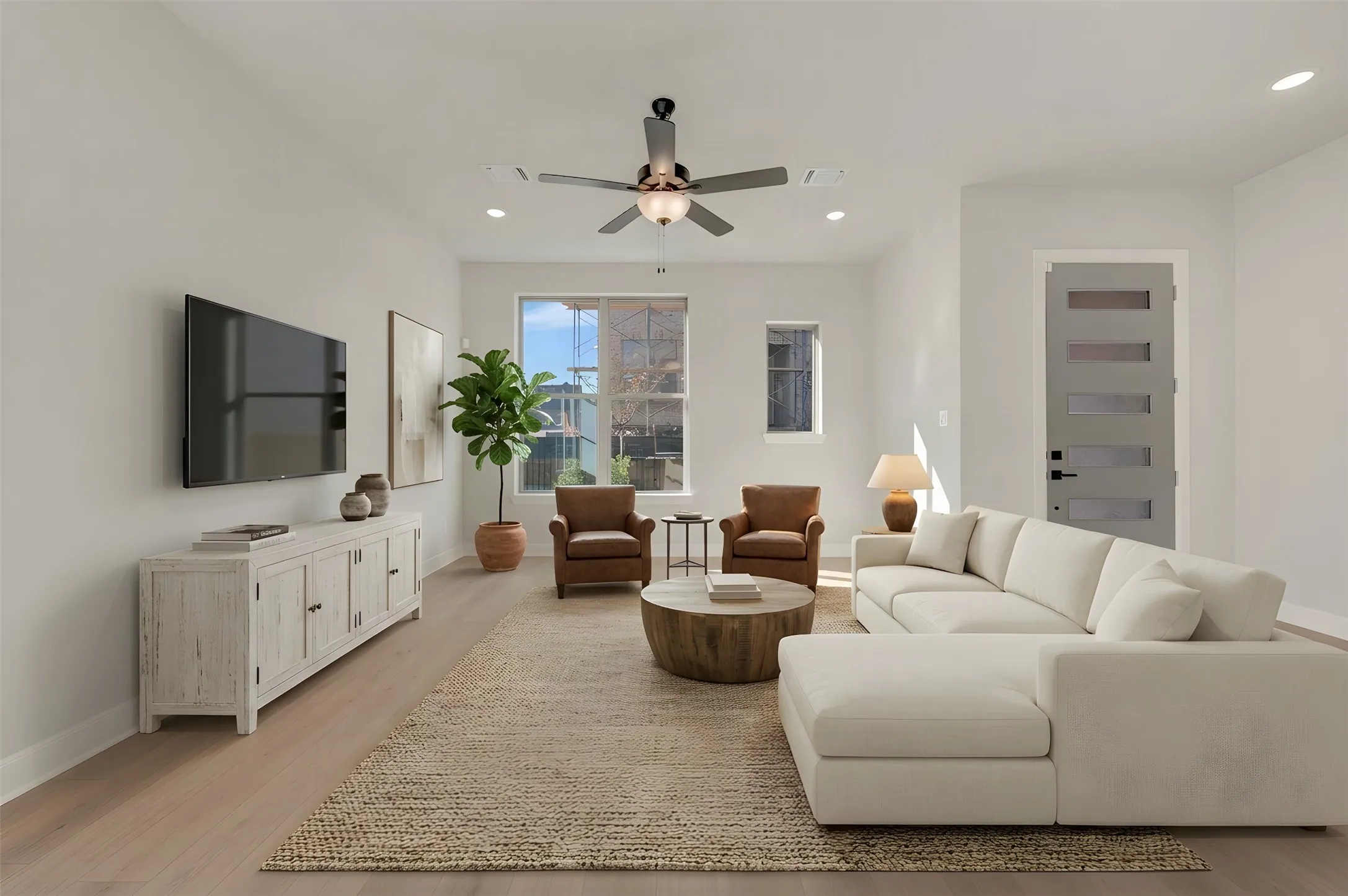 Spacious living area featuring light-toned wood-finish flooring, recessed lighting, and a ceiling fan