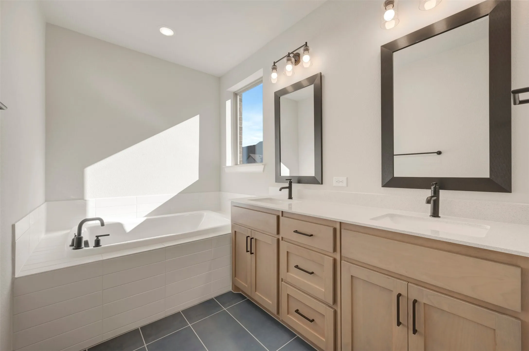 Dual vanity with light wood-finish cabinetry and white countertops