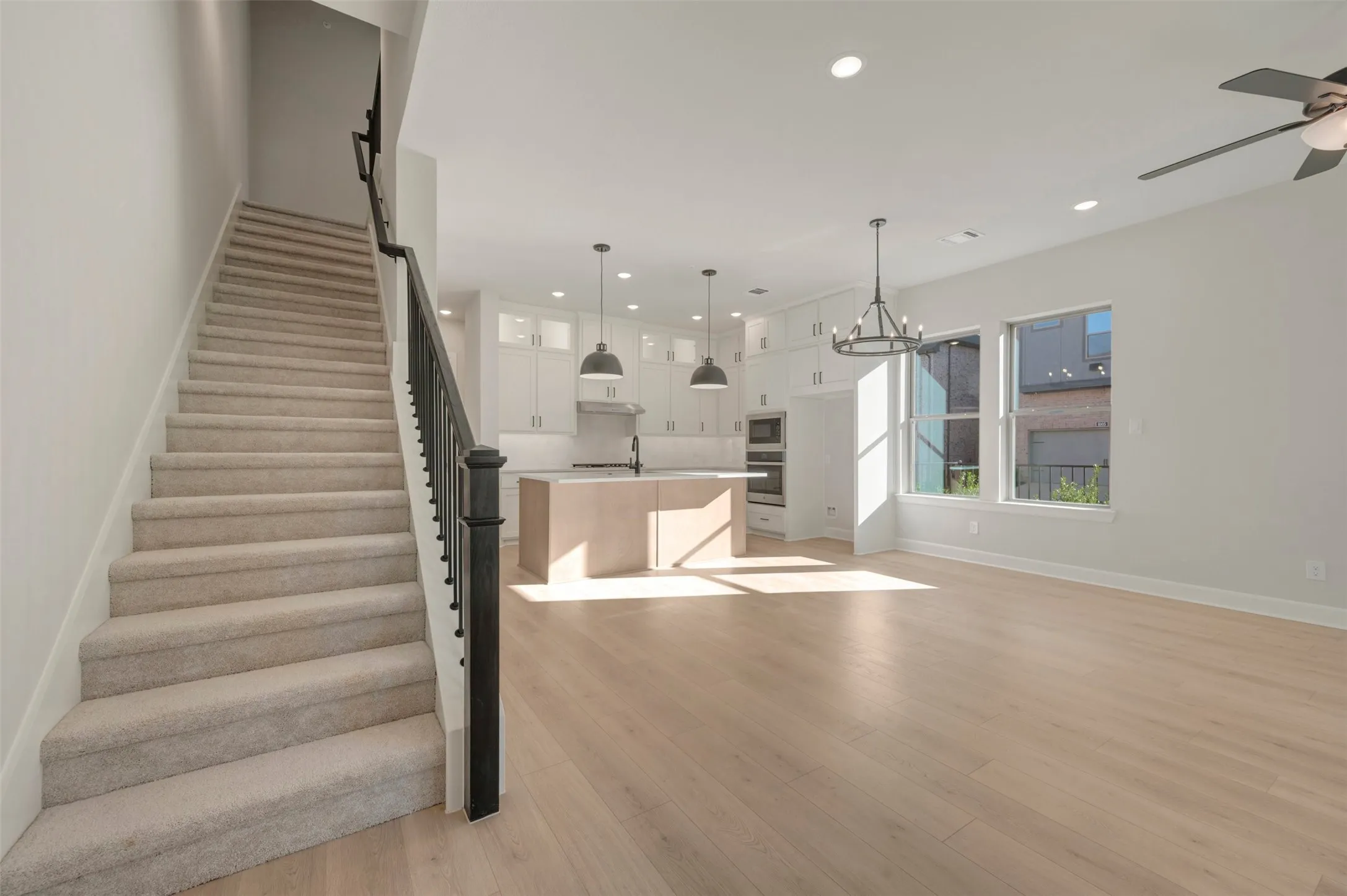 Open-concept living area with light wood-finish flooring, white walls, and recessed lighting
