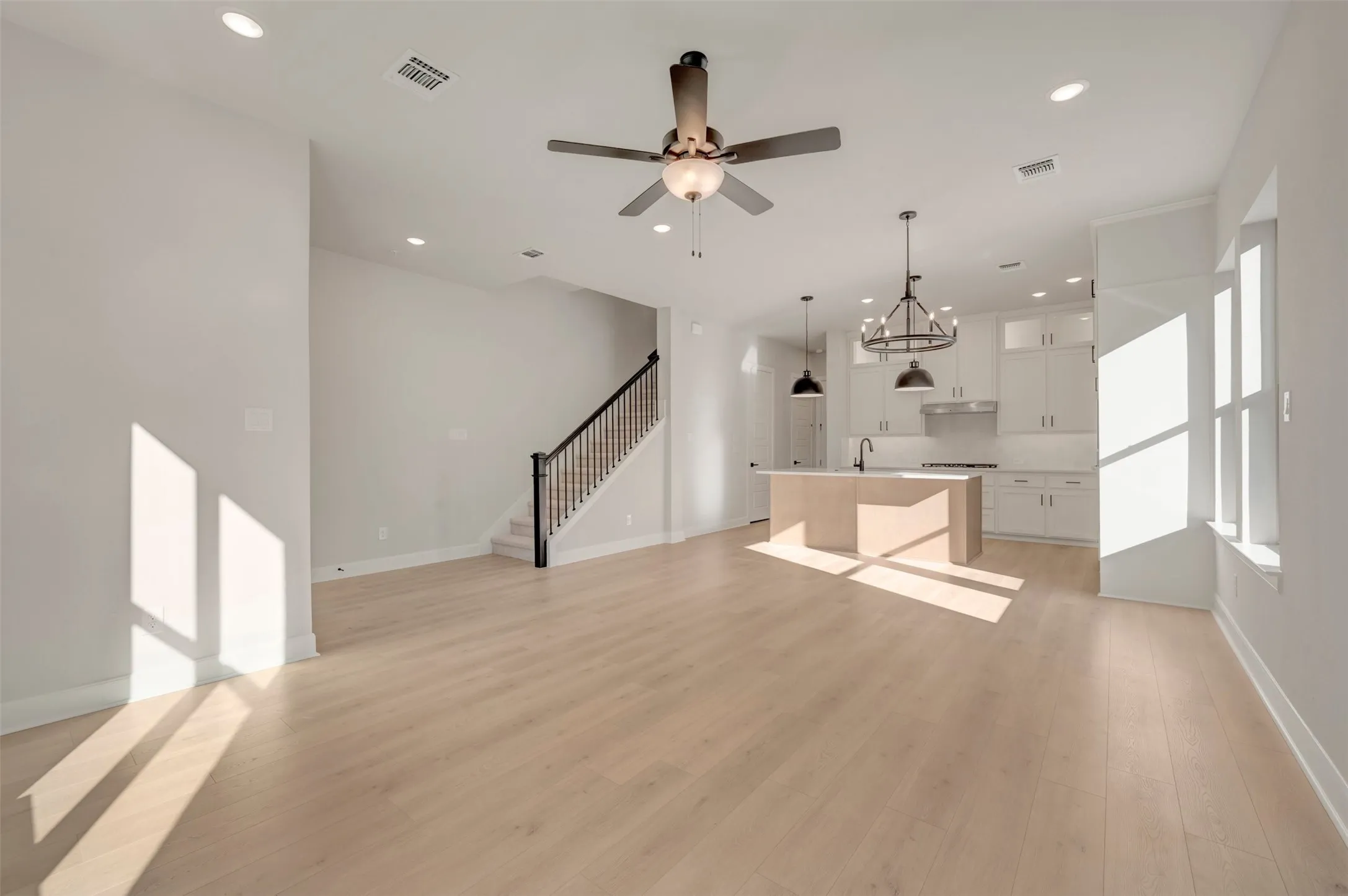 Open-concept living space featuring light wood-finish flooring, recessed lighting, and a contemporary ceiling fan