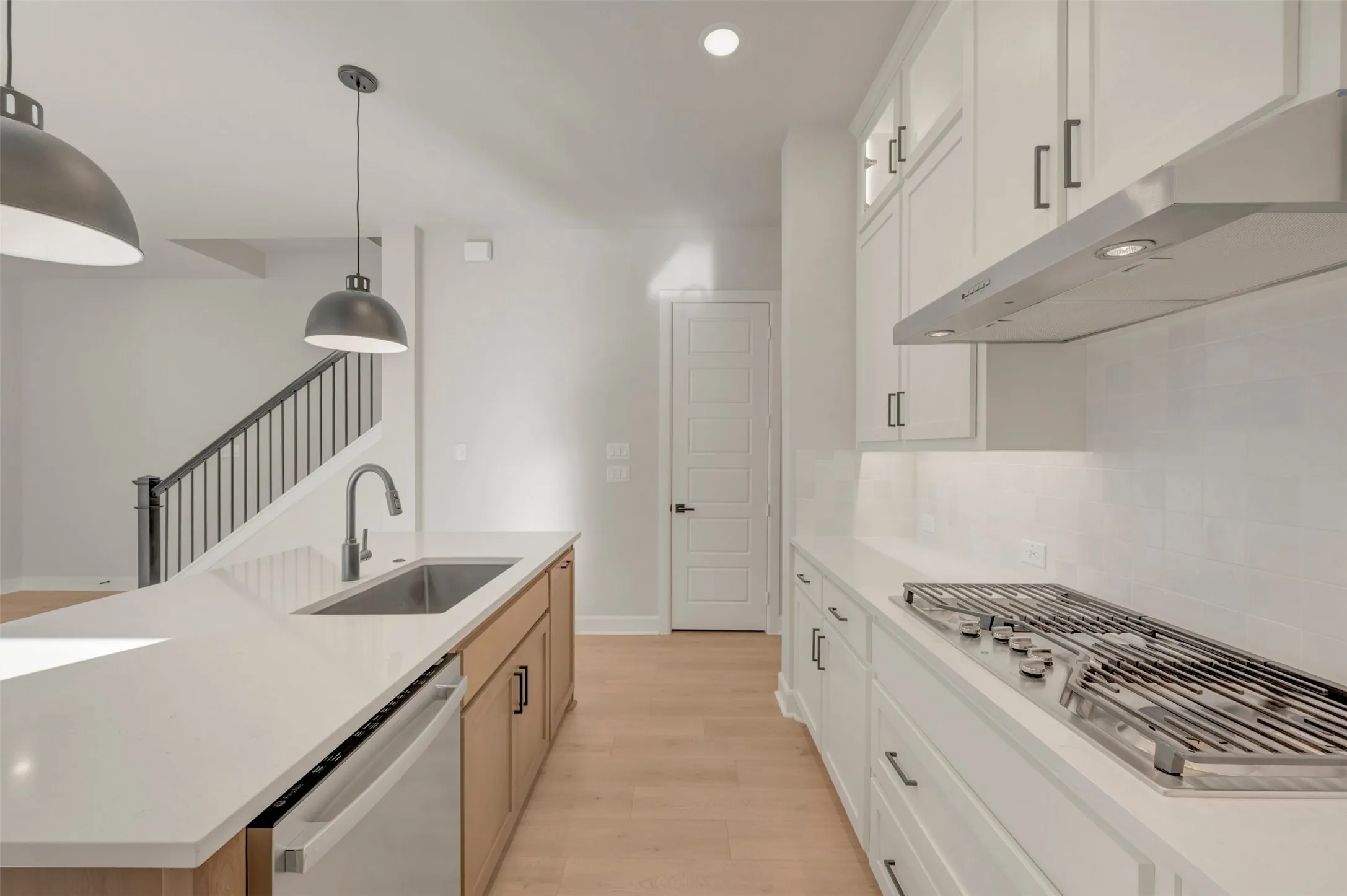 Kitchen featuring white cabinetry, light countertops, stainless steel appliances, and wood-finish flooring