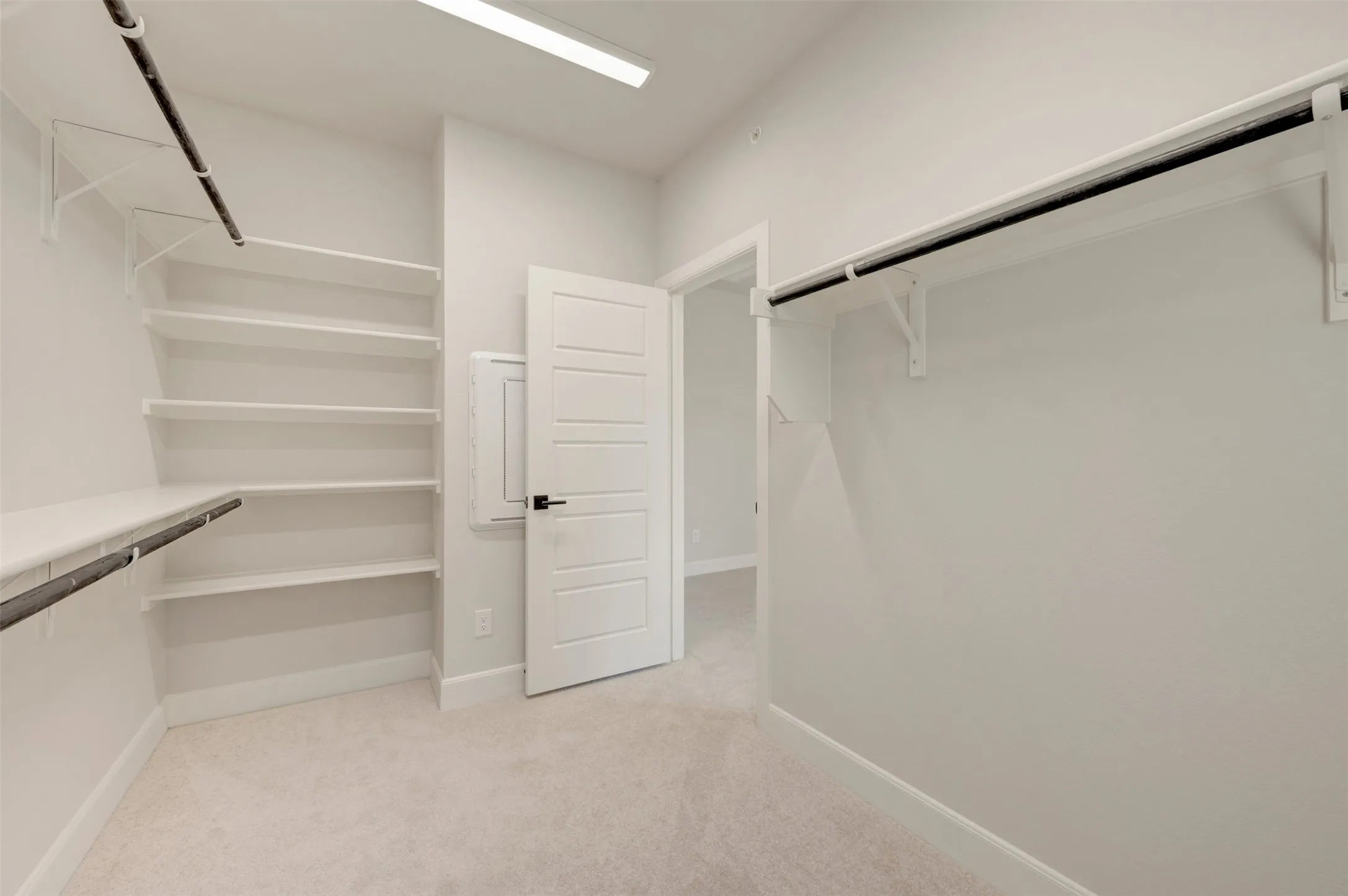 Recessed lighting, light-toned carpeting, white shelving units, white doors, and black door hardware