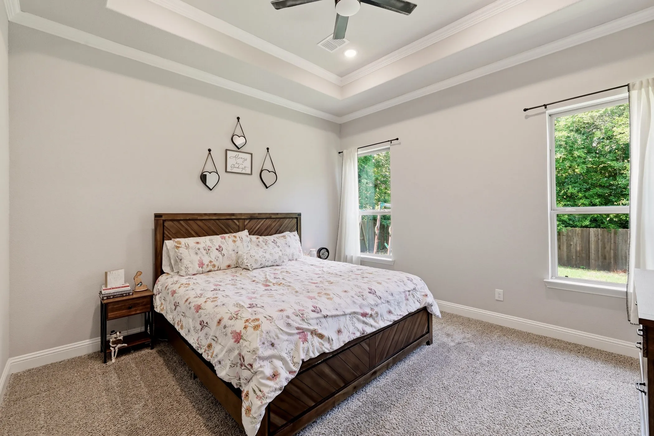 Light-filled room featuring a tray ceiling with crown molding, recessed lighting, and a ceiling fan