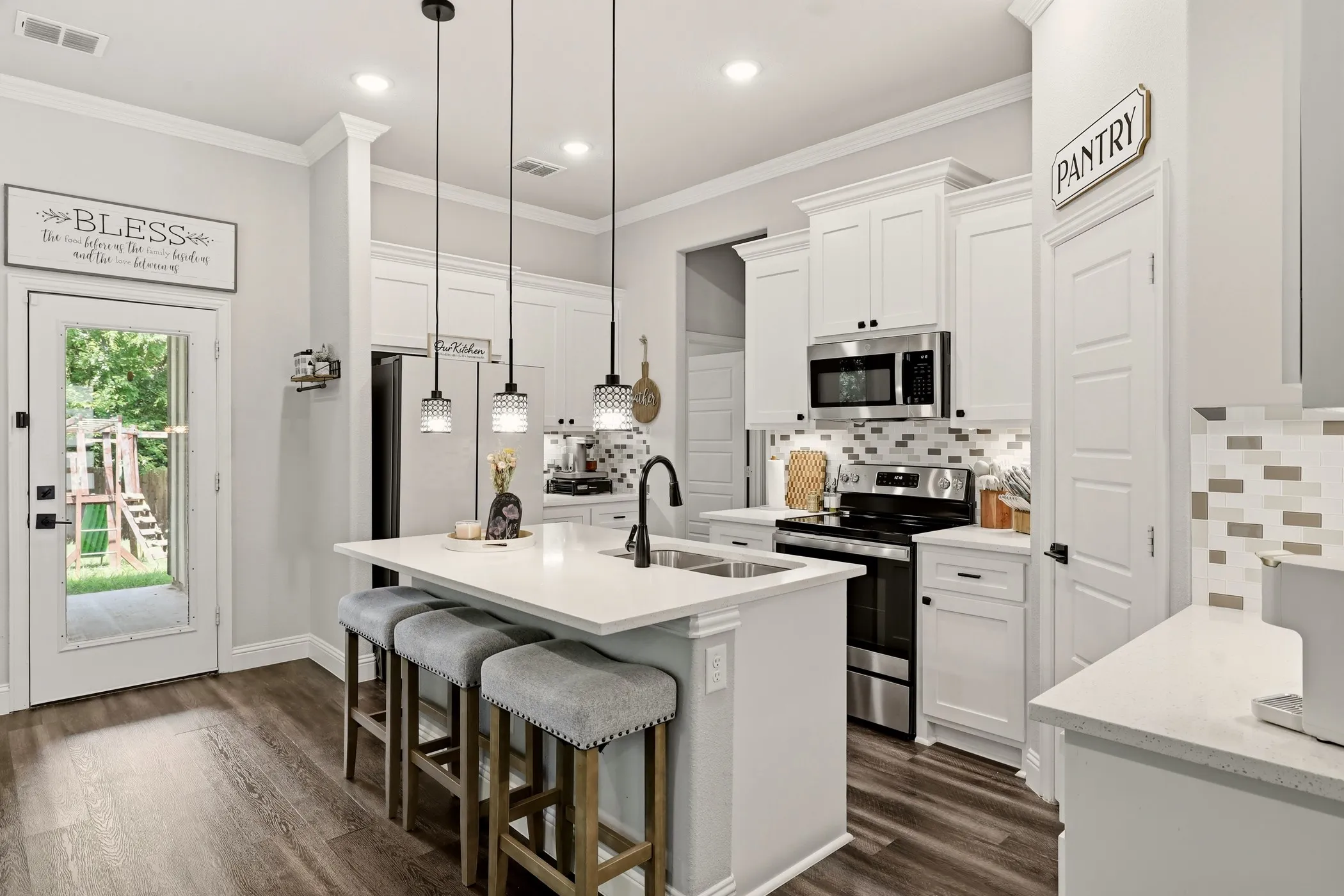 Modern kitchen featuring white cabinetry, stainless steel appliances, and a central island with a double basin sink