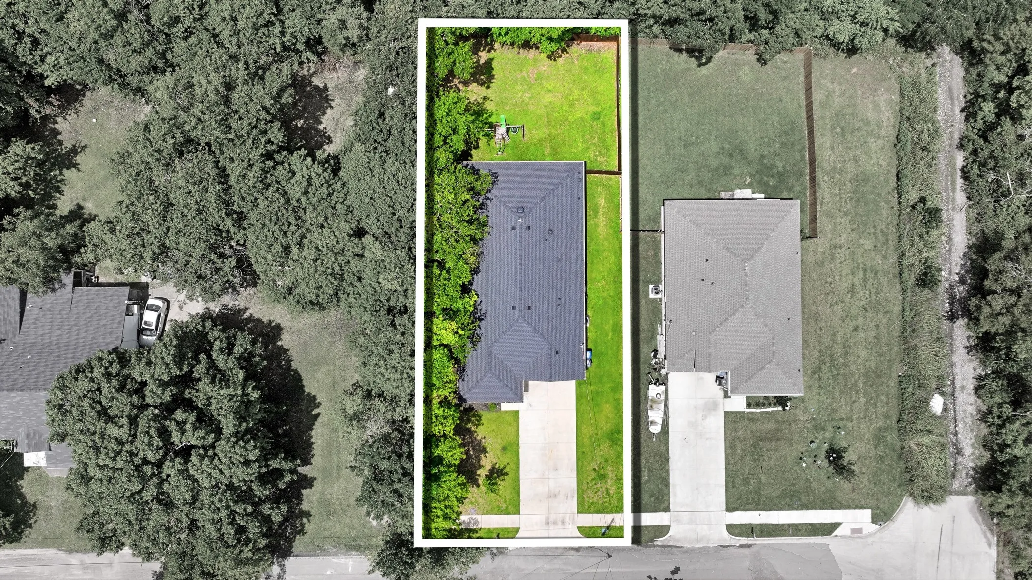 Aerial overview showcasing a property with a dark-pitched roof and a concrete driveway